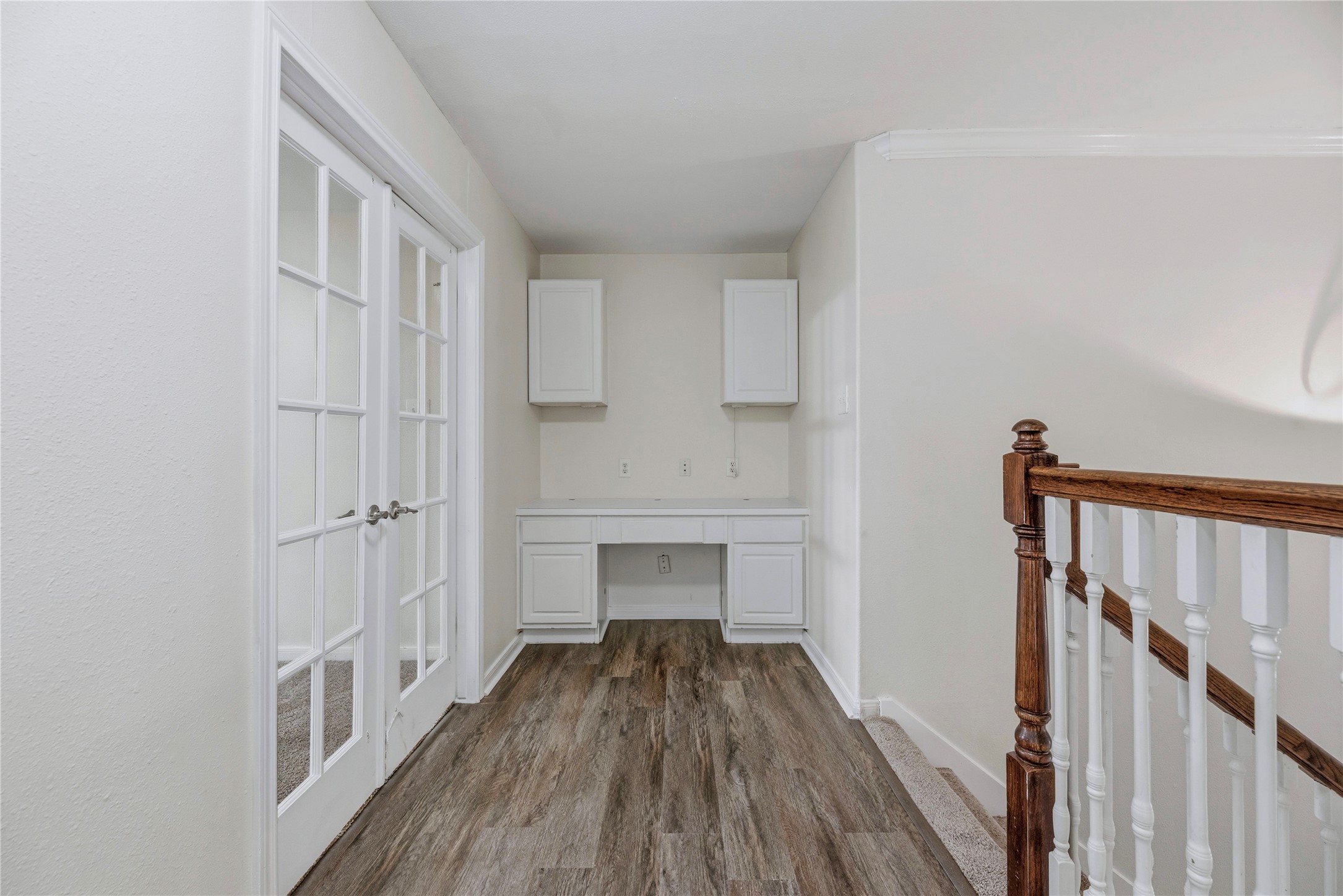A built-in desk and upper cabinets create a ready spot for a laptop or household organization beside the upstairs French-door room.