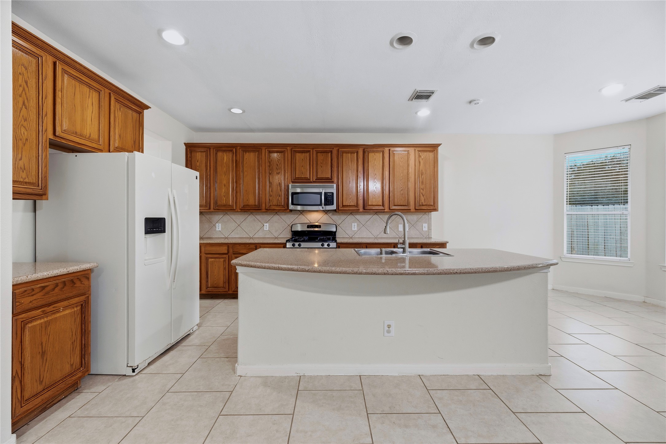 The central island adds a generous work surface, while cabinets along the back wall help keep kitchen essentials close to the cooking area.