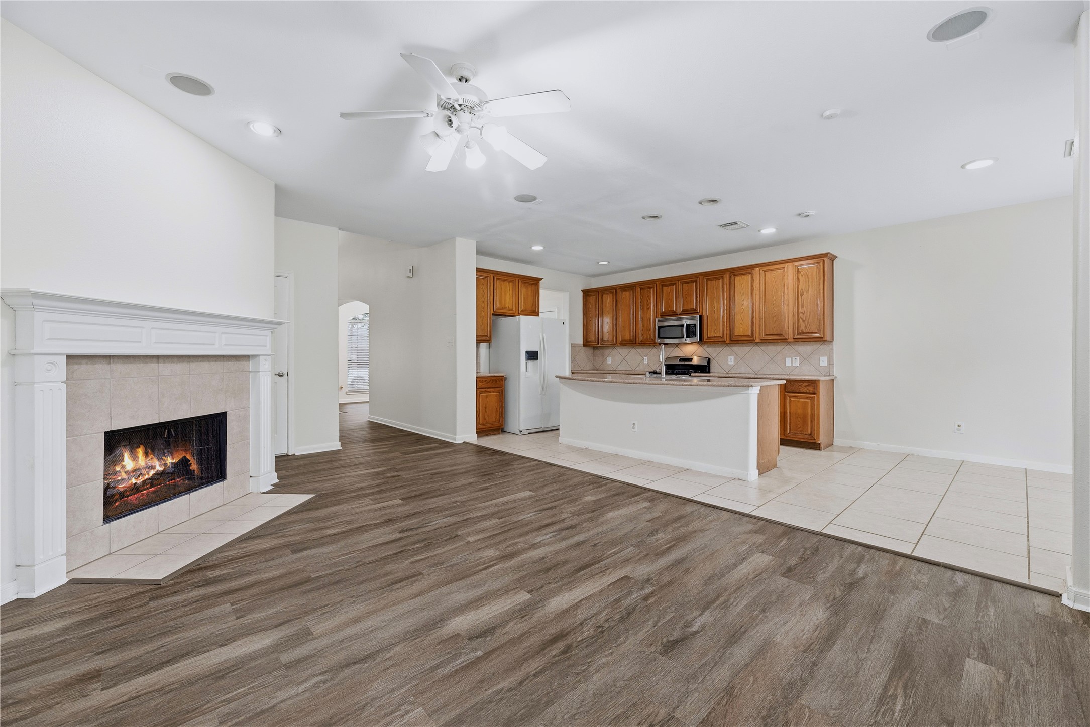 The family room opens directly to the kitchen, so conversations can continue while meals come together, with the fireplace in view from both spaces.