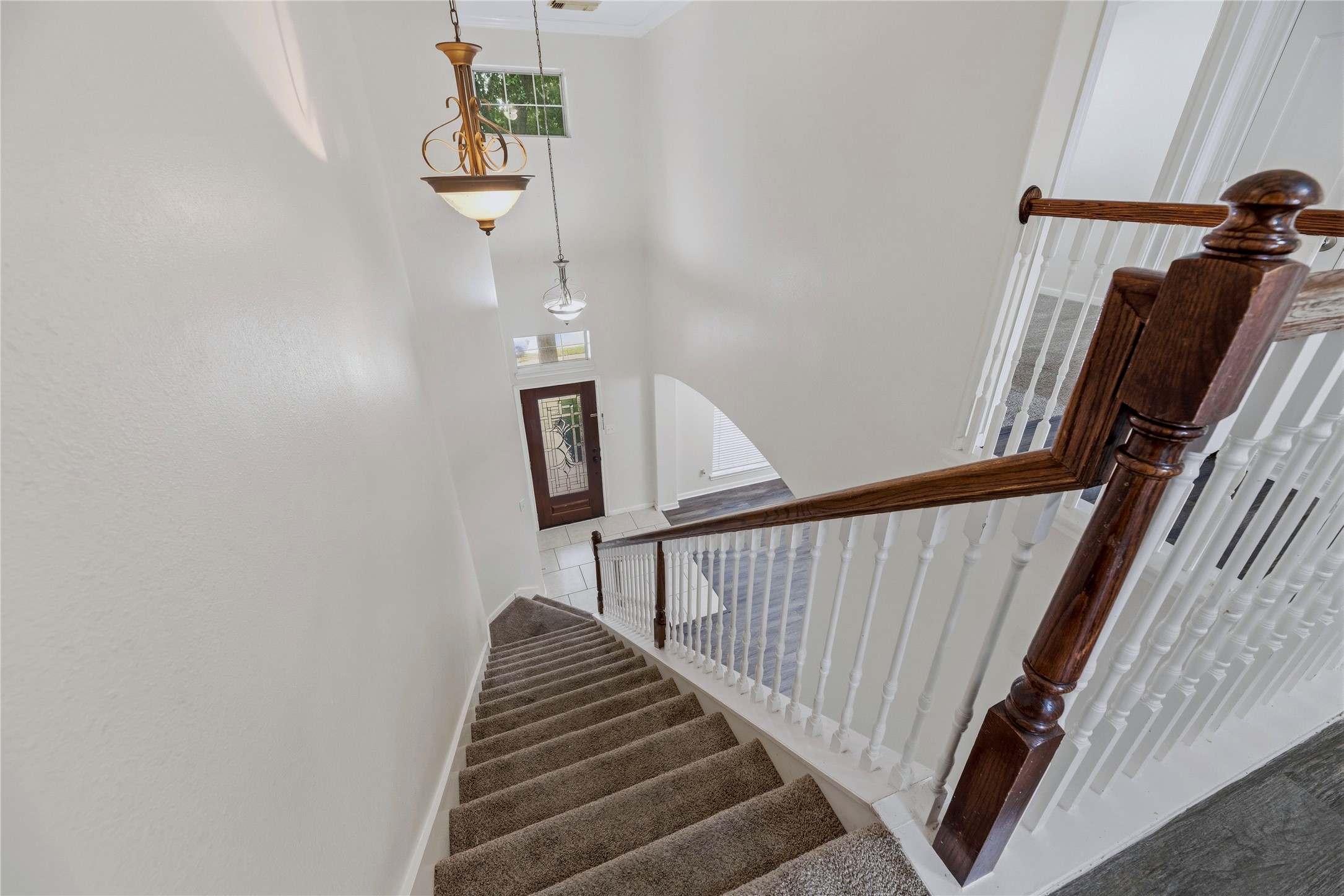The stair landing looks over the tall foyer, with an open railing that keeps the entry connected visually to the upper level.