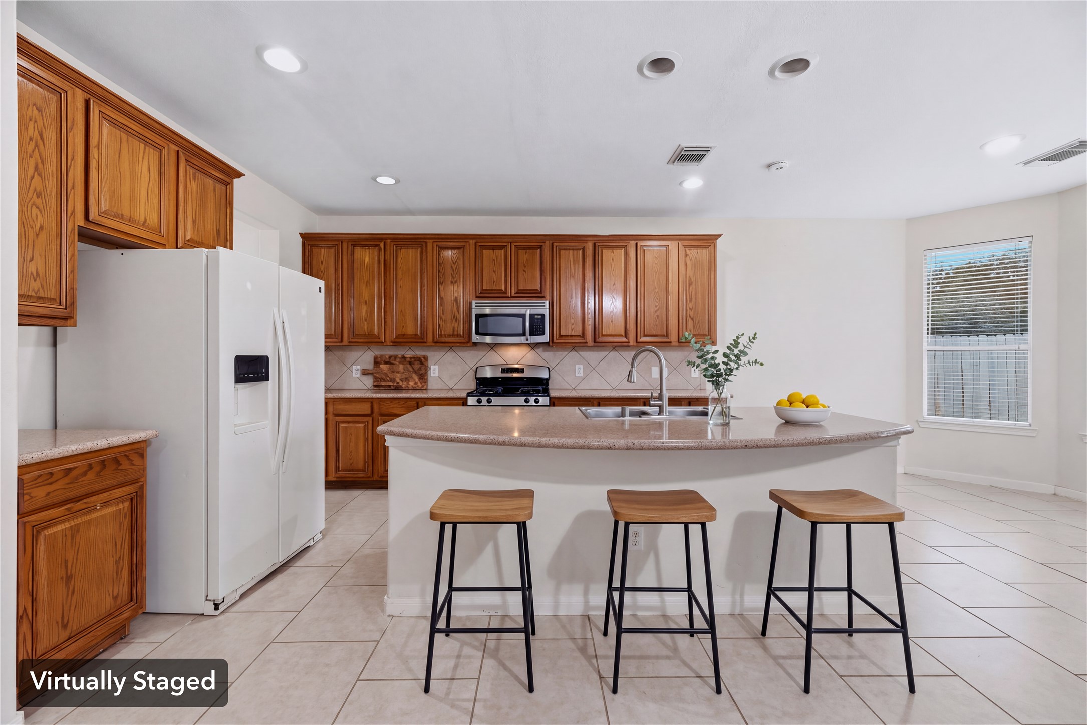 Virtually staged to illustrate casual seating at the island and its connection to the surrounding kitchen. Furniture shown is digital.