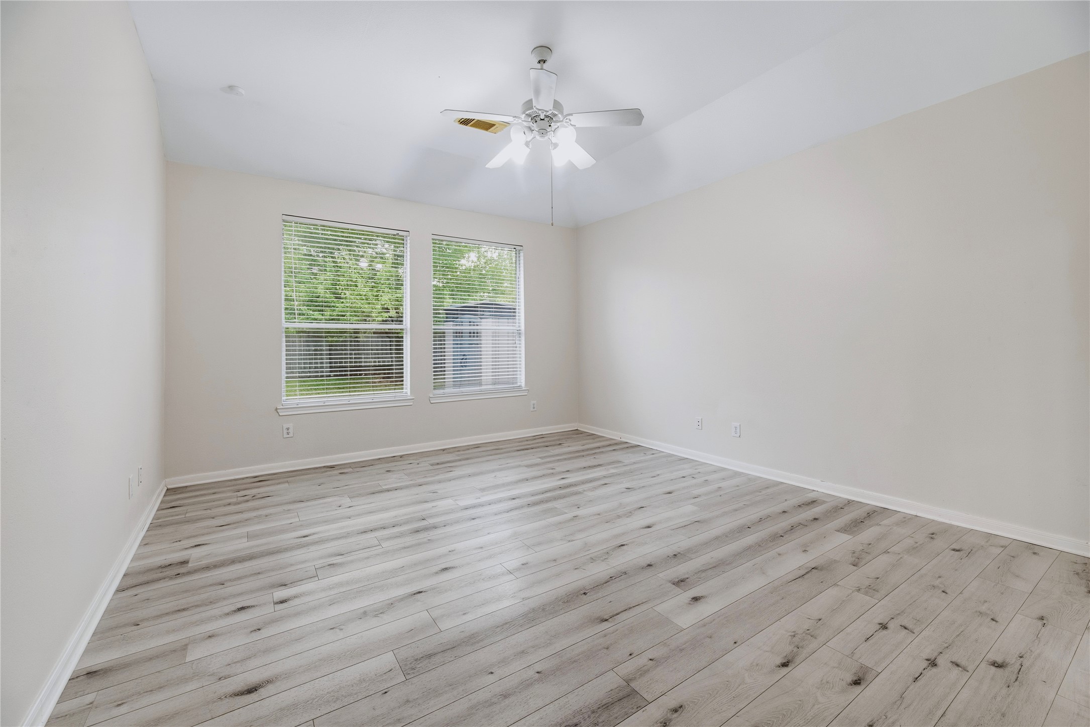 The unfurnished primary bedroom shows the available floor space, paired windows and ceiling fan, so you can picture how your own furniture will fit.