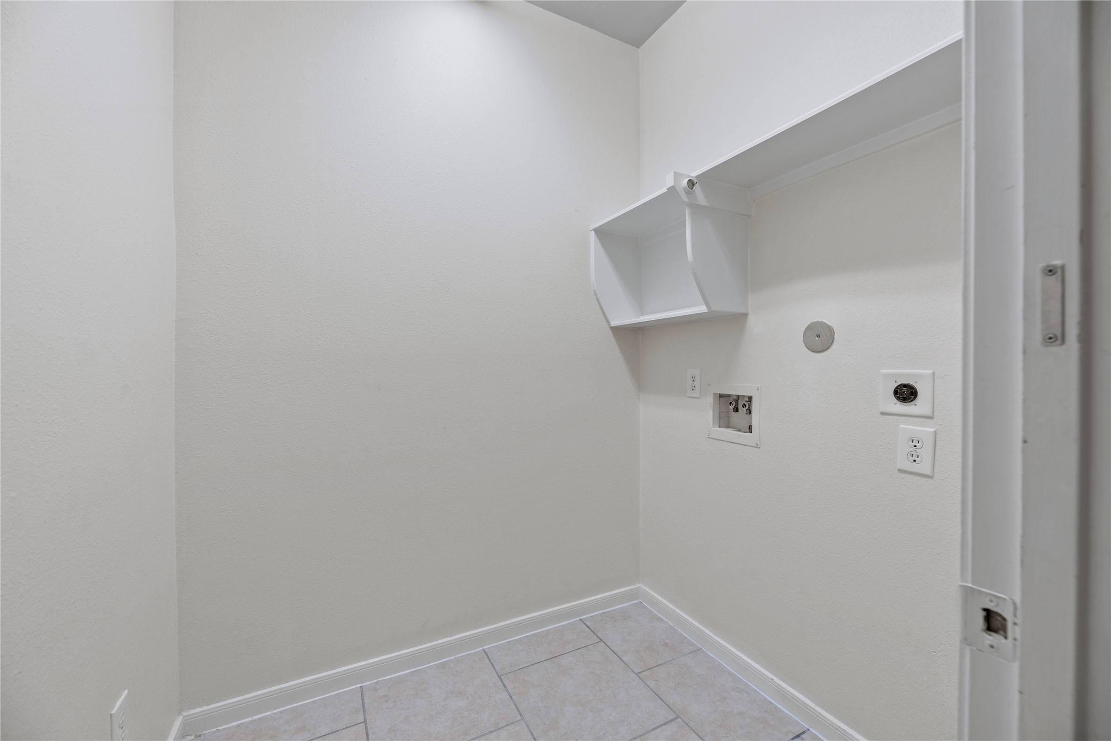 A dedicated utility room keeps laundry in its own space, with washer and dryer connections, an overhead shelf and a hanging rod for organization.