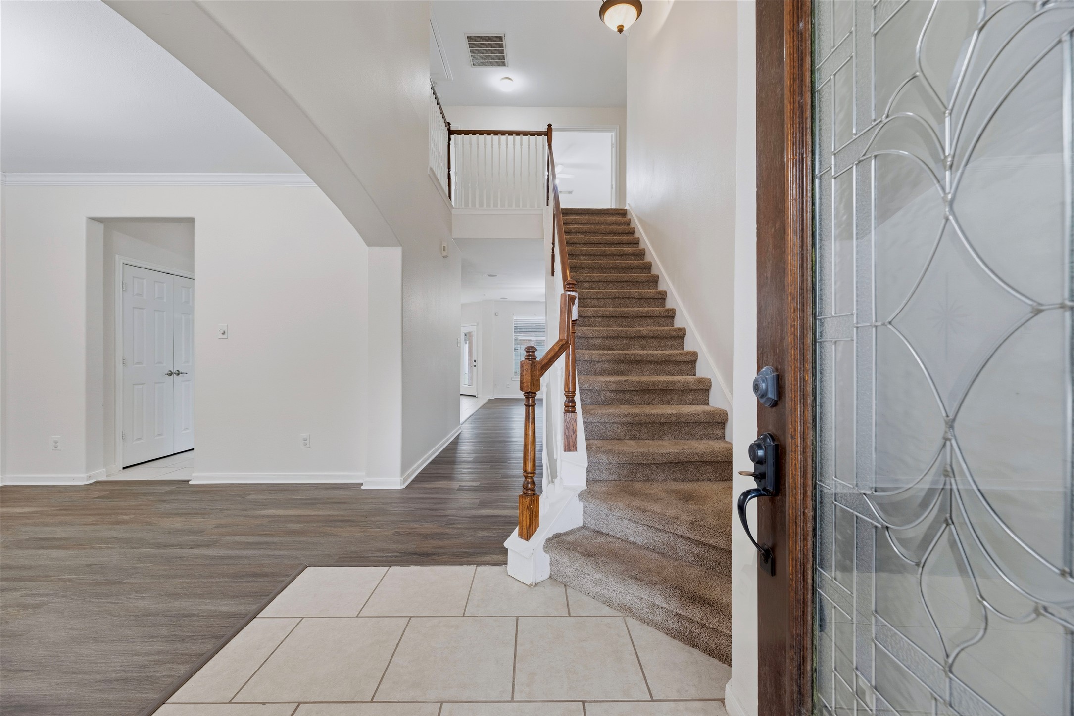 Step through the decorative-glass front door into a tall entry, with open sightlines to the front living area and a staircase leading upstairs. Step through the decorative-glass front door into a tall entry, with open sightlines to the front living area and a staircase leading upstairs.