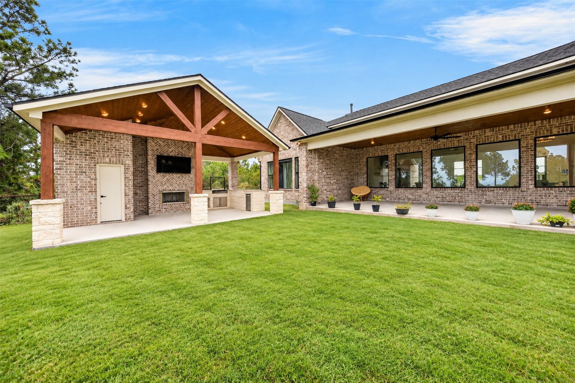 The brick rear elevation, covered pavilion, and broad lawn come together to extend the home's living space outdoors.
