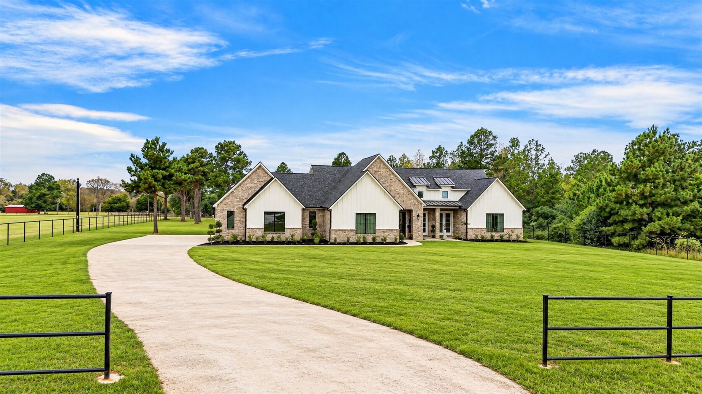 A curved concrete drive leads to the brick garage wing, where varied rooflines add architectural interest to the home's approach.