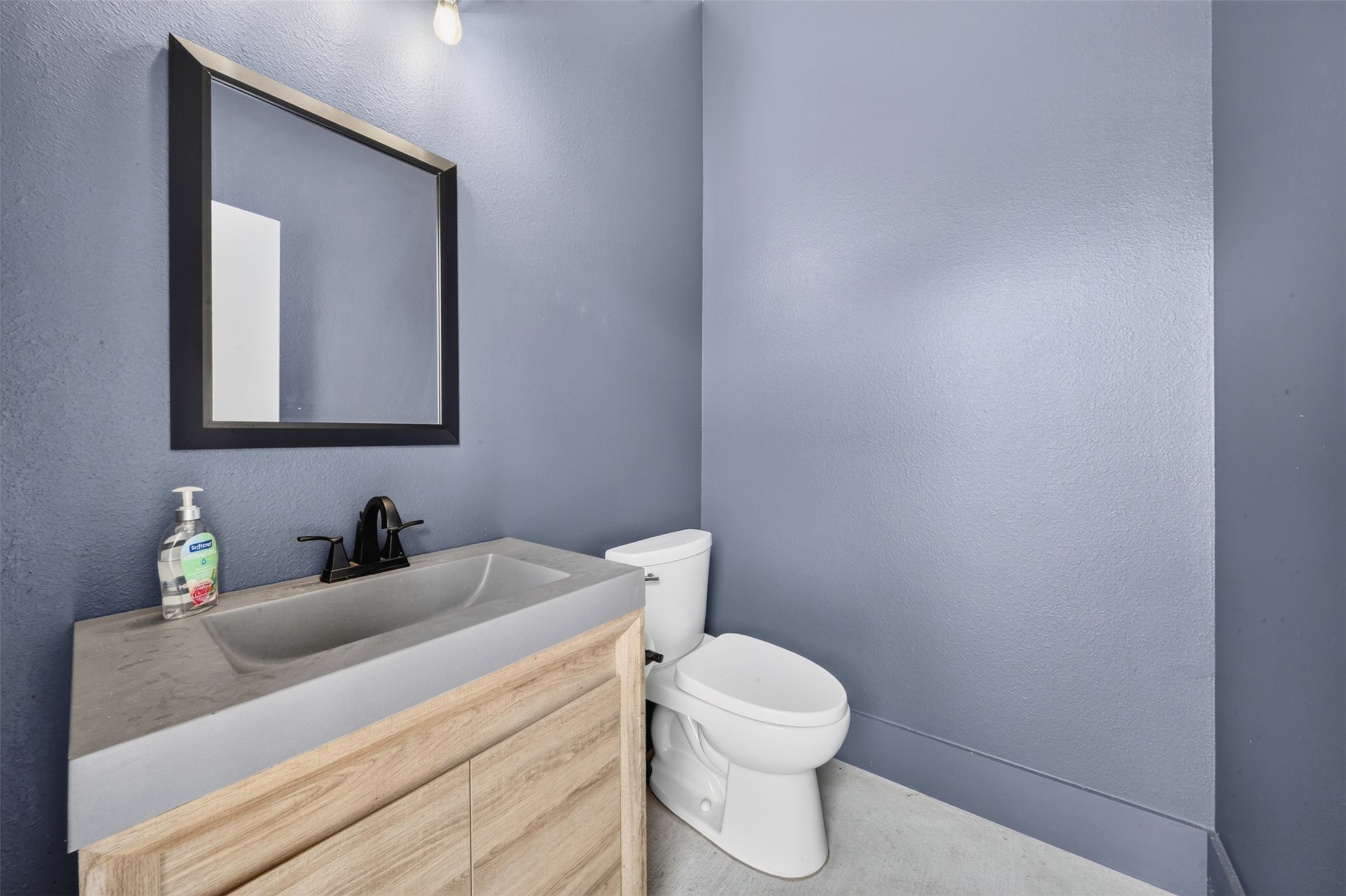 Blue-gray walls and a light wood vanity bring color and warmth to the powder bath while keeping the finishes simple and clean.
