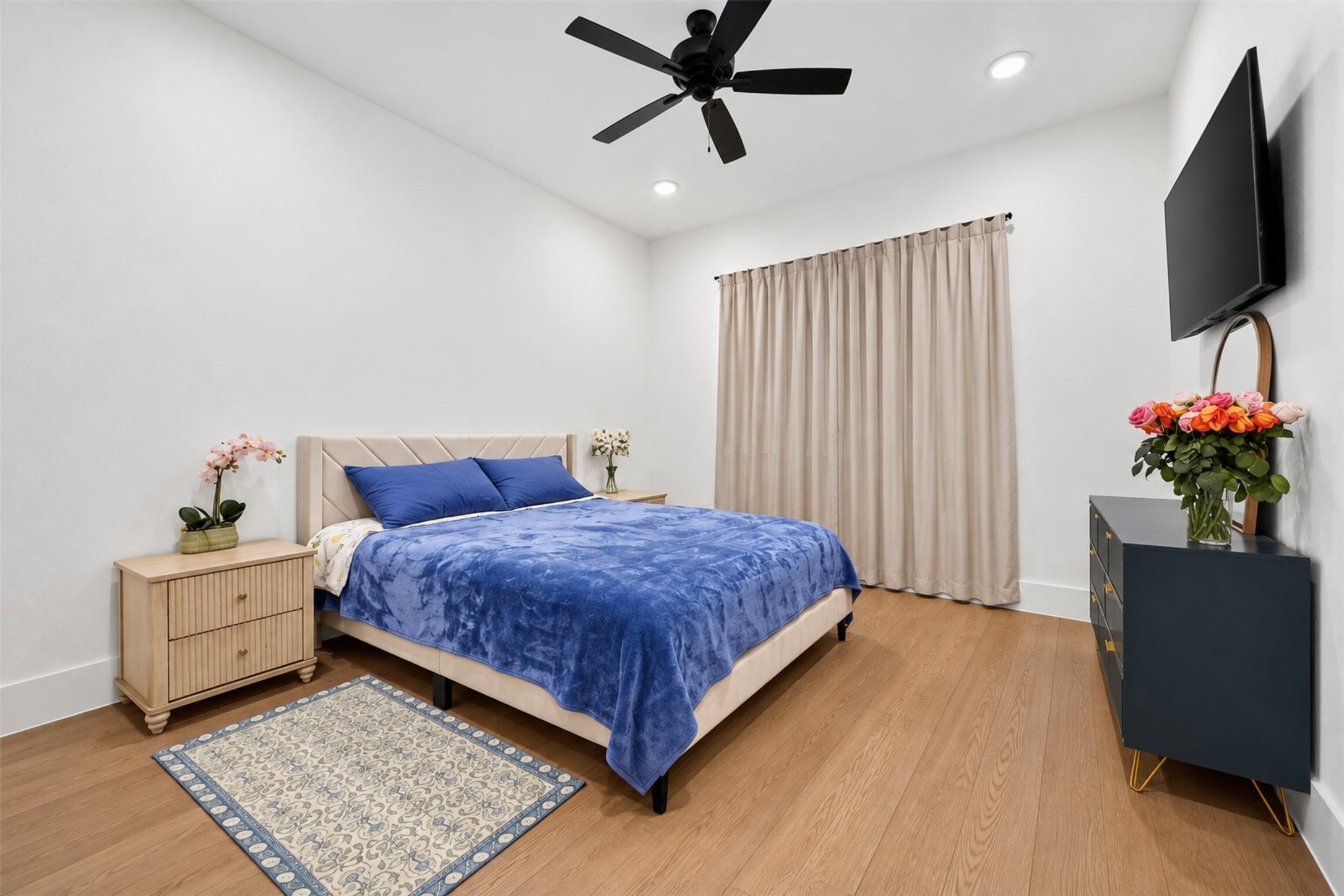Wide windows and a ceiling fan give this secondary bedroom a bright, open feel, while wood-look flooring continues the home's finishes.