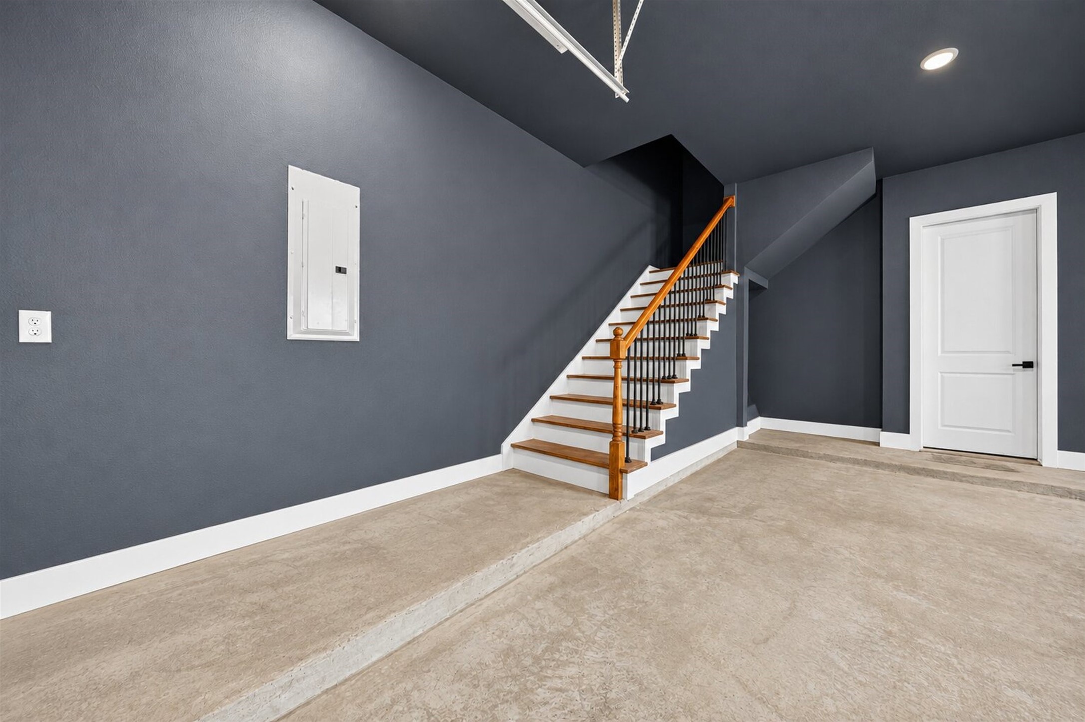 Wood treads and black iron balusters lead to attic access above the finished garage.