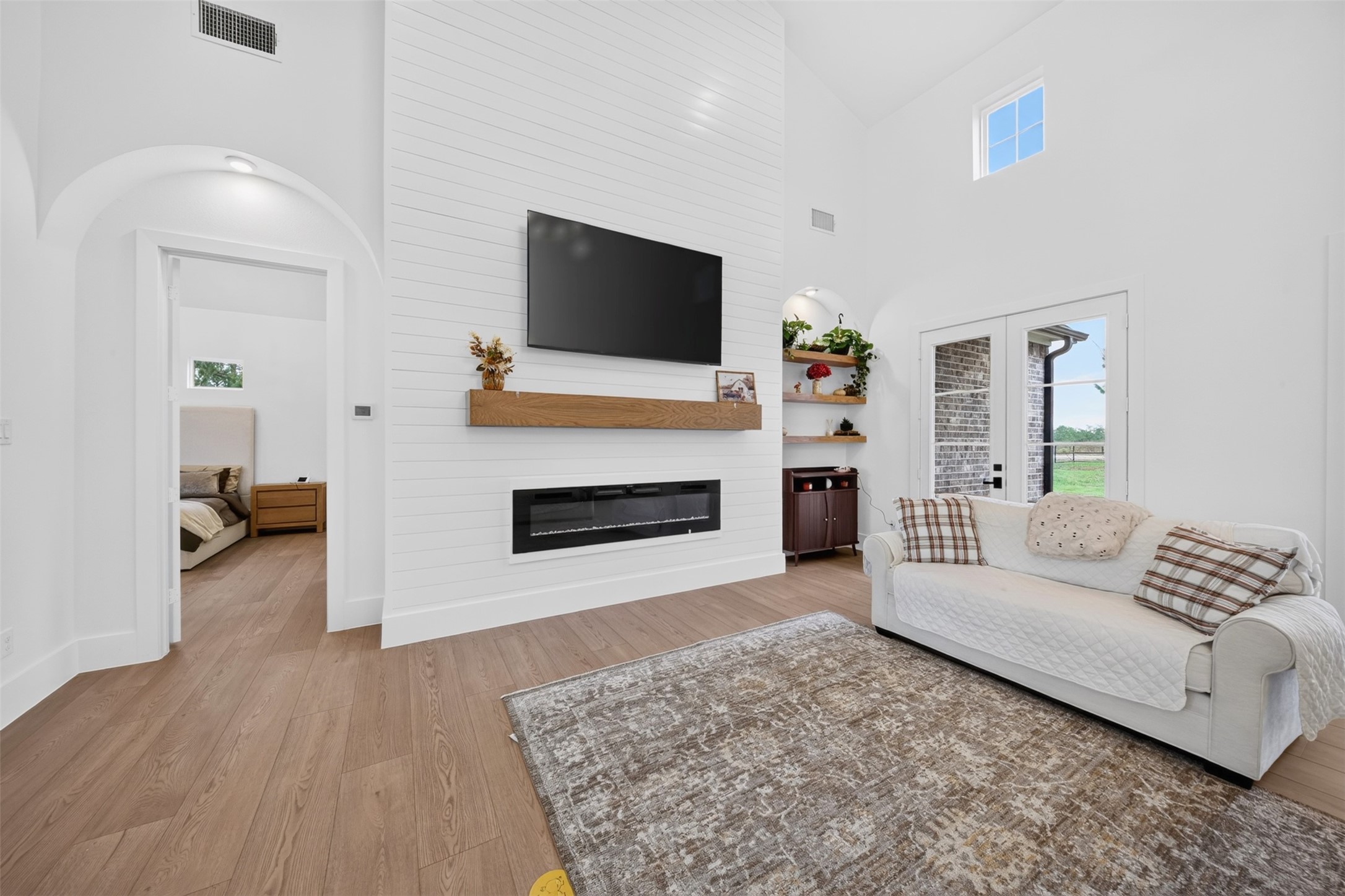 A shiplap fireplace wall, substantial wood mantel, and arched niches add architectural detail to the living room.