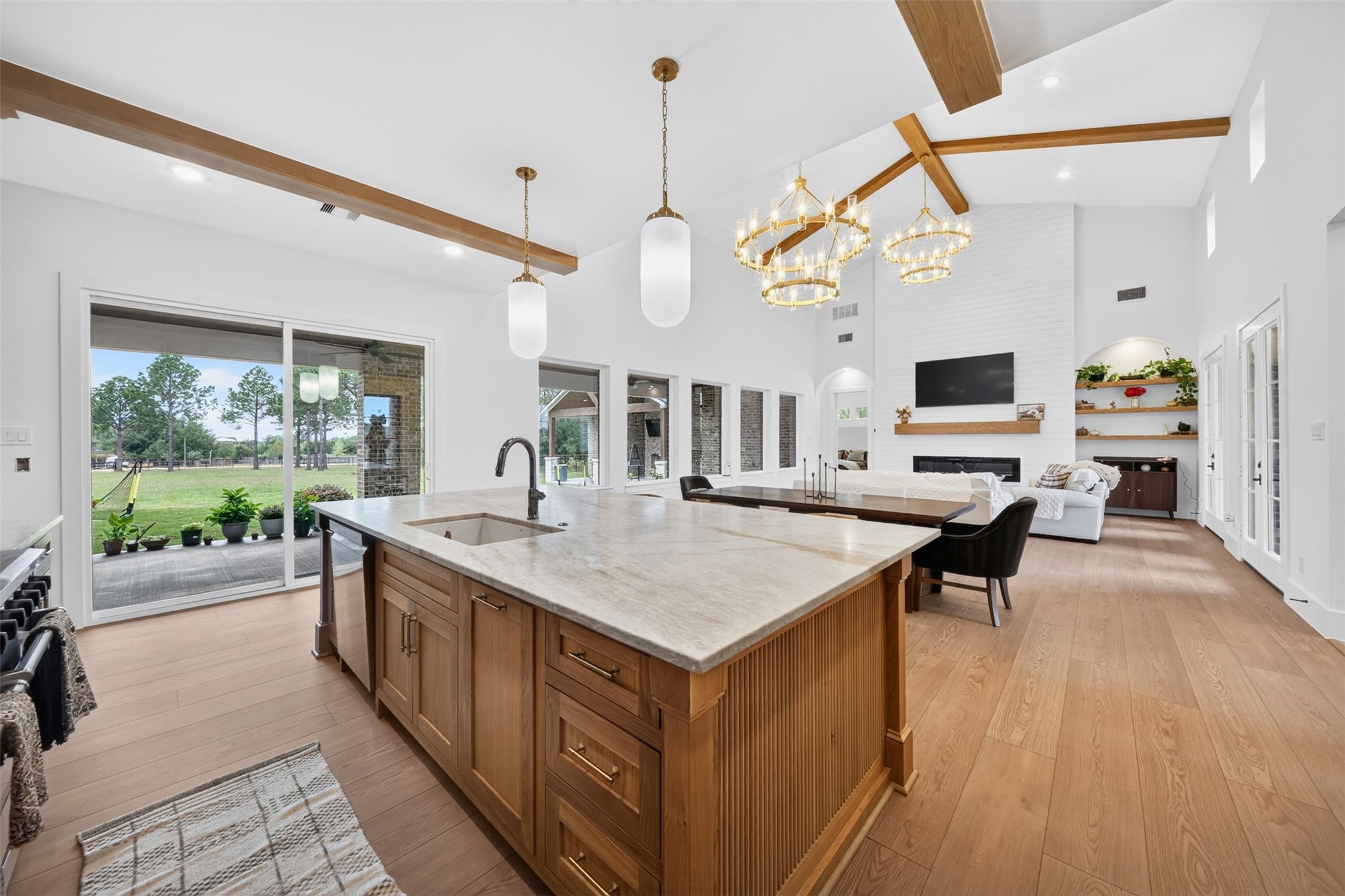 A generous stone island with a fluted wood base and apron-front sink overlooks the family room and connects the kitchen to the living space.