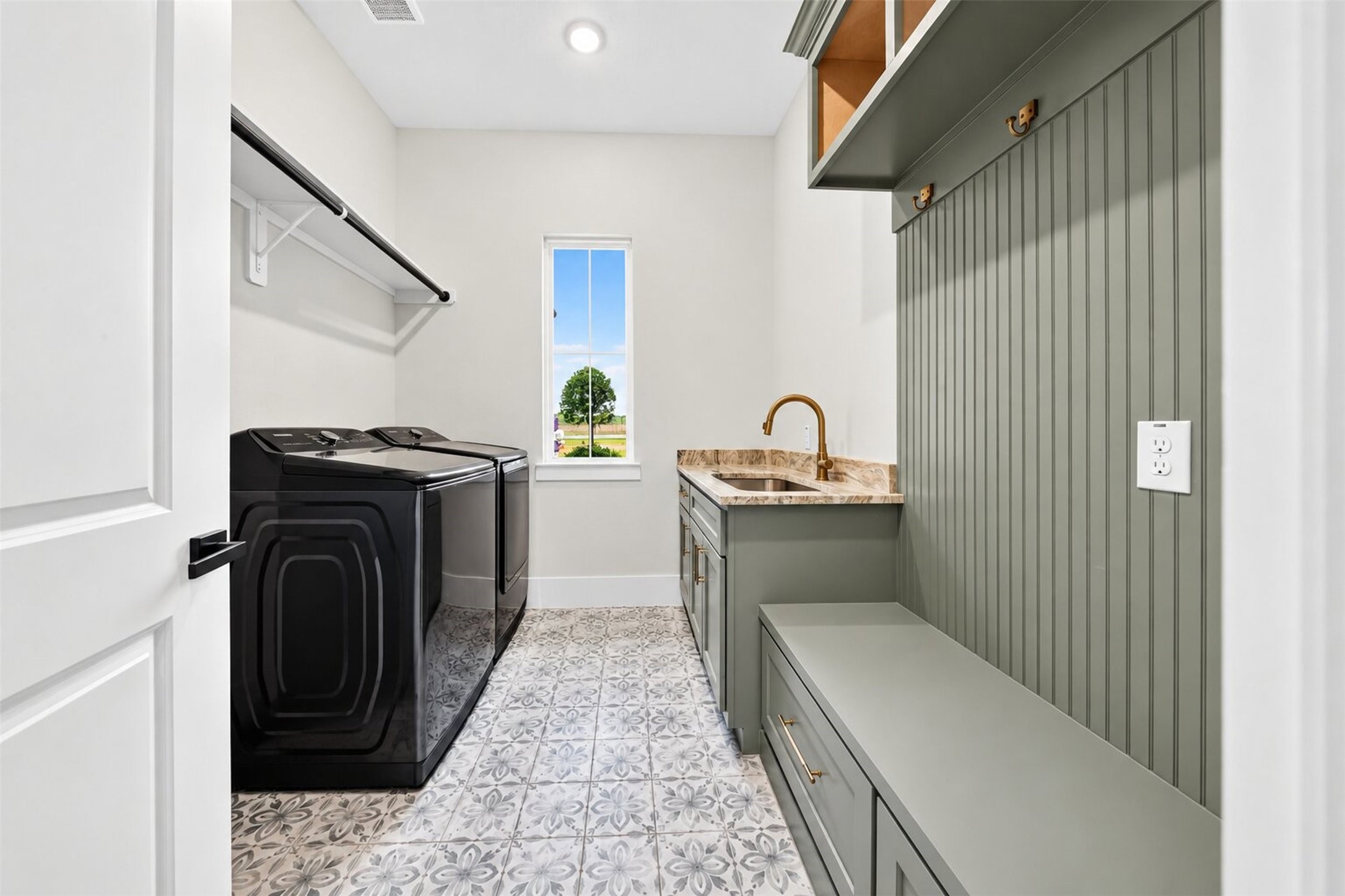 Built-in cabinetry and a utility sink add everyday function, while patterned tile brings detail to the laundry room floor.