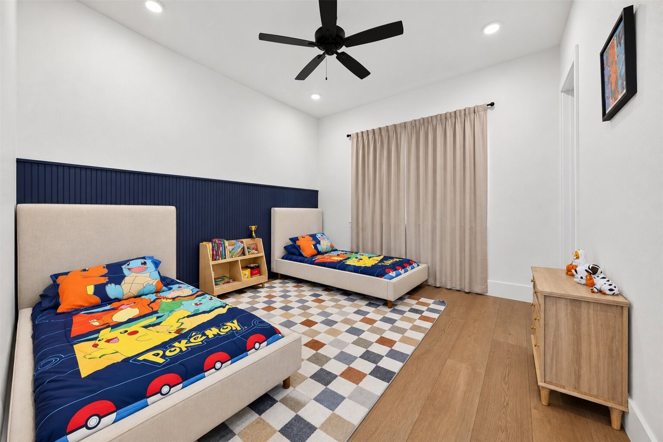 Navy board-and-batten adds a distinctive architectural accent to this bedroom, complemented by a ceiling fan and wide window.
