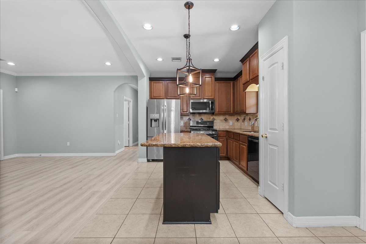 A pantry door sits just off the kitchen, and the tile-to-wood flooring transition marks a clean division between the kitchen and the adjoining living space.