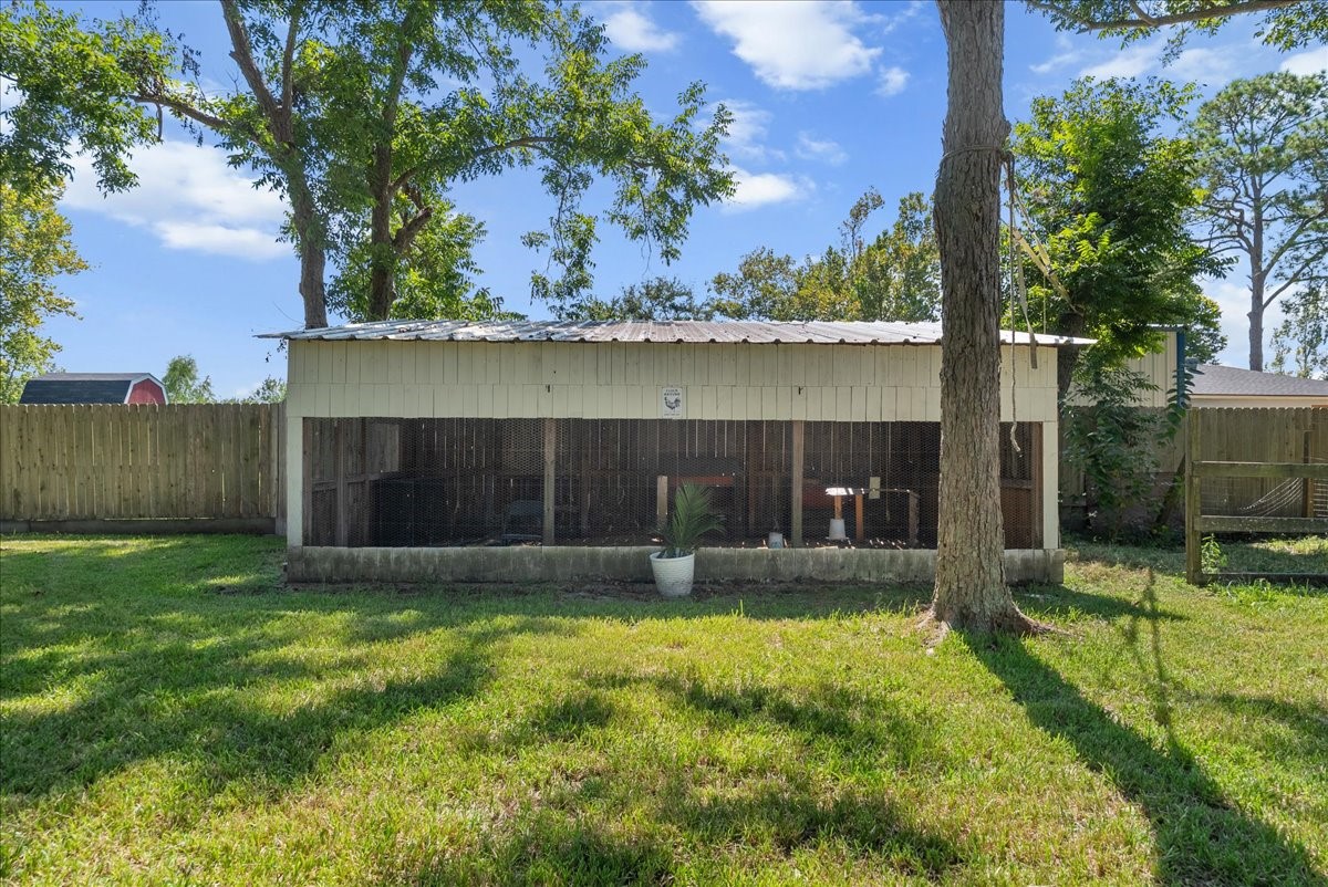 Tucked beneath mature shade trees, this oversized chicken coop features a metal roof, enclosed wire run, and electrical access, plenty of room to run a hobby farm or keep backyard livestock.