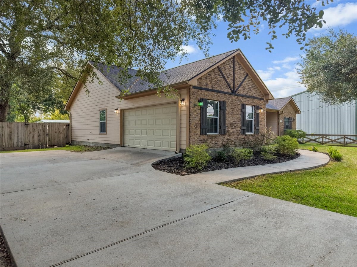 Tucked beneath a canopy of mature oaks, this brick ranch charms from the curb with dormer accents, a deep covered porch, and a rich wood front door that sets a warm, welcoming tone.