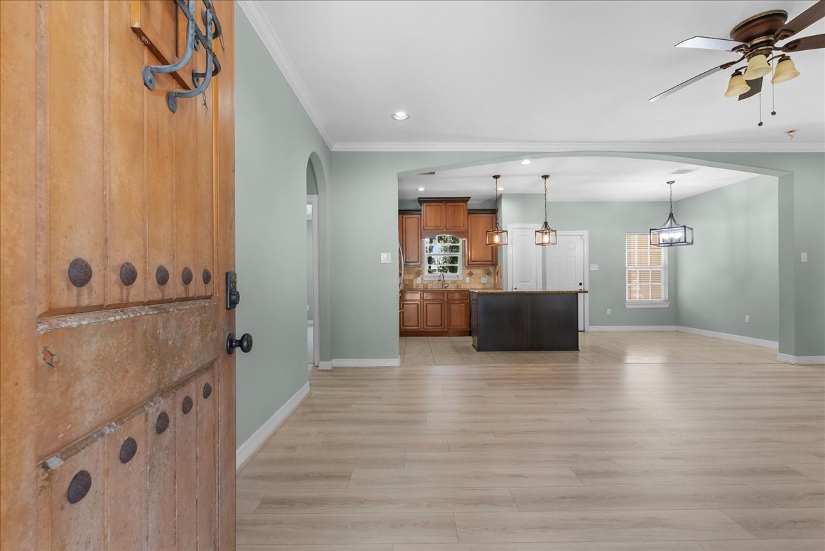 Step through the front door into a bright, open floor plan where wide-plank flooring and soft sage tones carry through the living space into the kitchen.