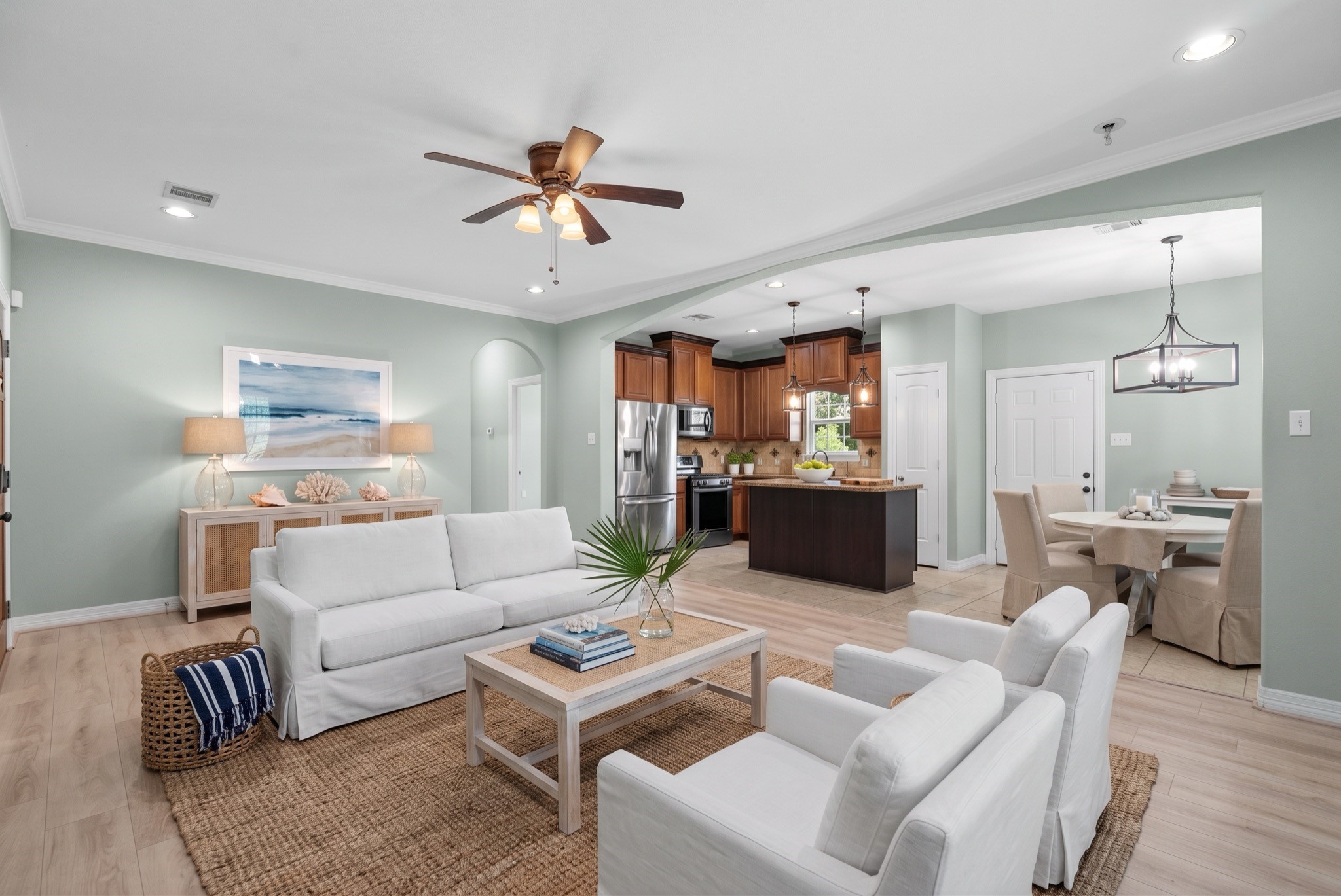 Wide-plank flooring runs throughout, and a ceiling fan plus recessed lighting complete the main living area, while an arched doorway adds architectural detail between rooms.