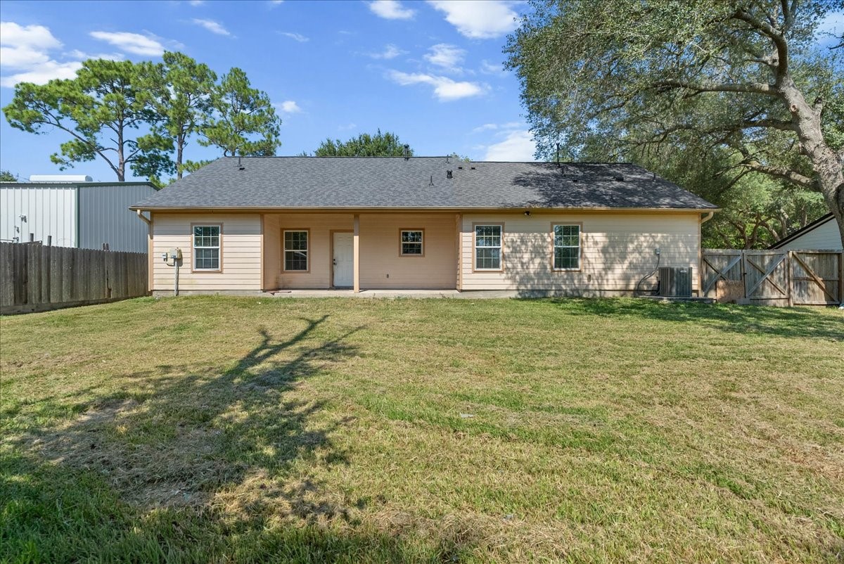 A covered back porch spans a good portion of the rear elevation, complete with an exterior door leading in from the yard. A double-gate side entry and privacy fence enclose the full width of the property, keeping the backyard secure.