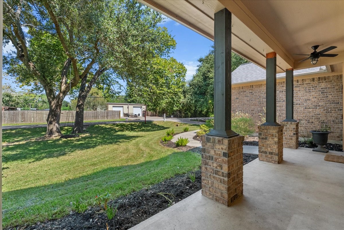 Relax on the covered front porch with a ceiling fan overhead and views out to mature shade trees and a manicured lawn, the kind of spot that turns coffee on the porch into a daily ritual.
