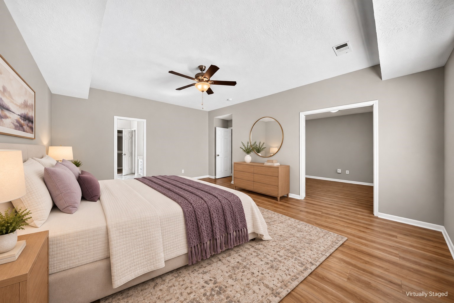 Primary Bedroom: Generously proportioned primary retreat with wood-look flooring, ceiling fan and ample space for a complete bedroom arrangement.