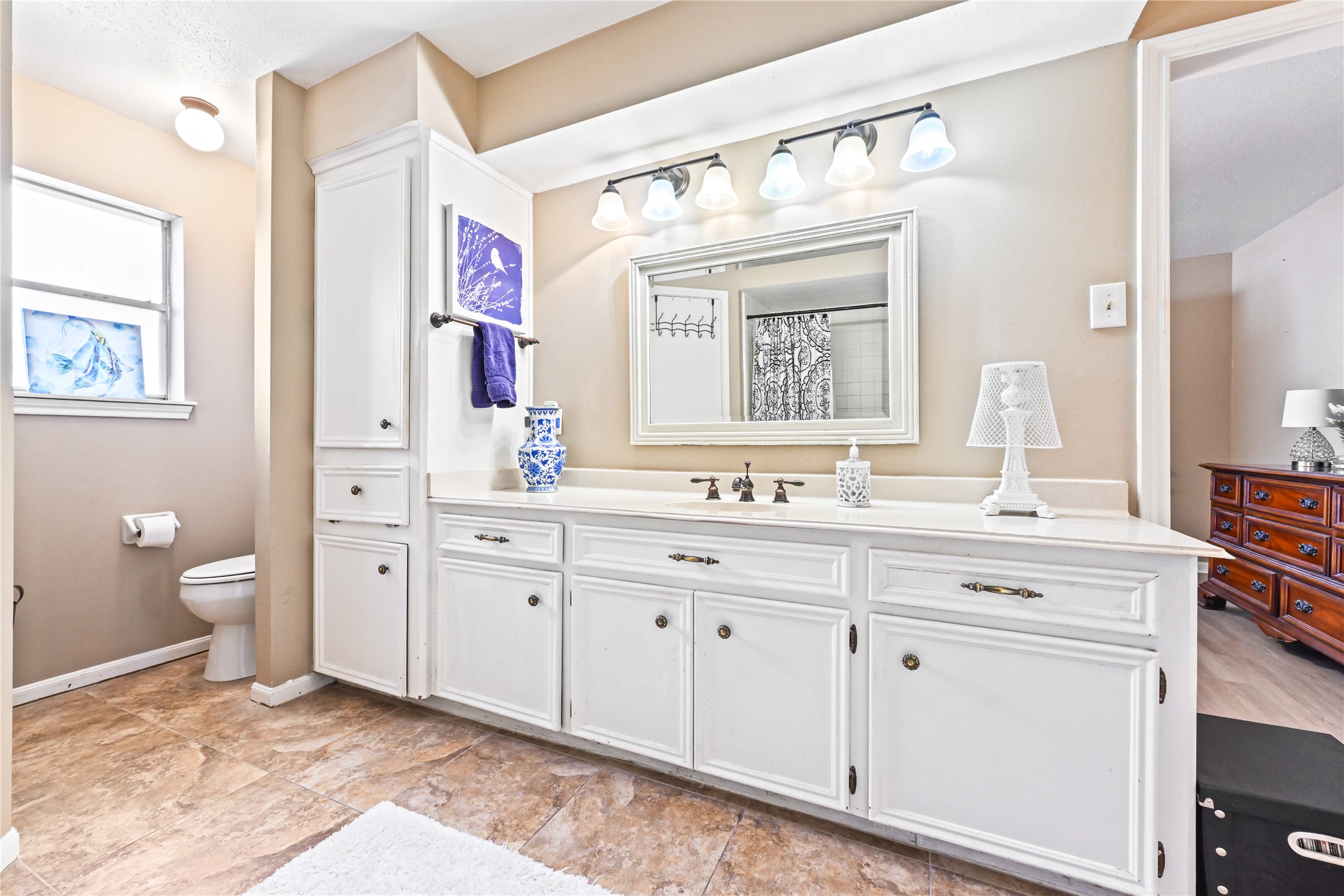 Spacious bathroom featuring a double vanity with ample storage, elegant lighting, and a large mirror, complemented by a neutral color palette and tasteful decor.
