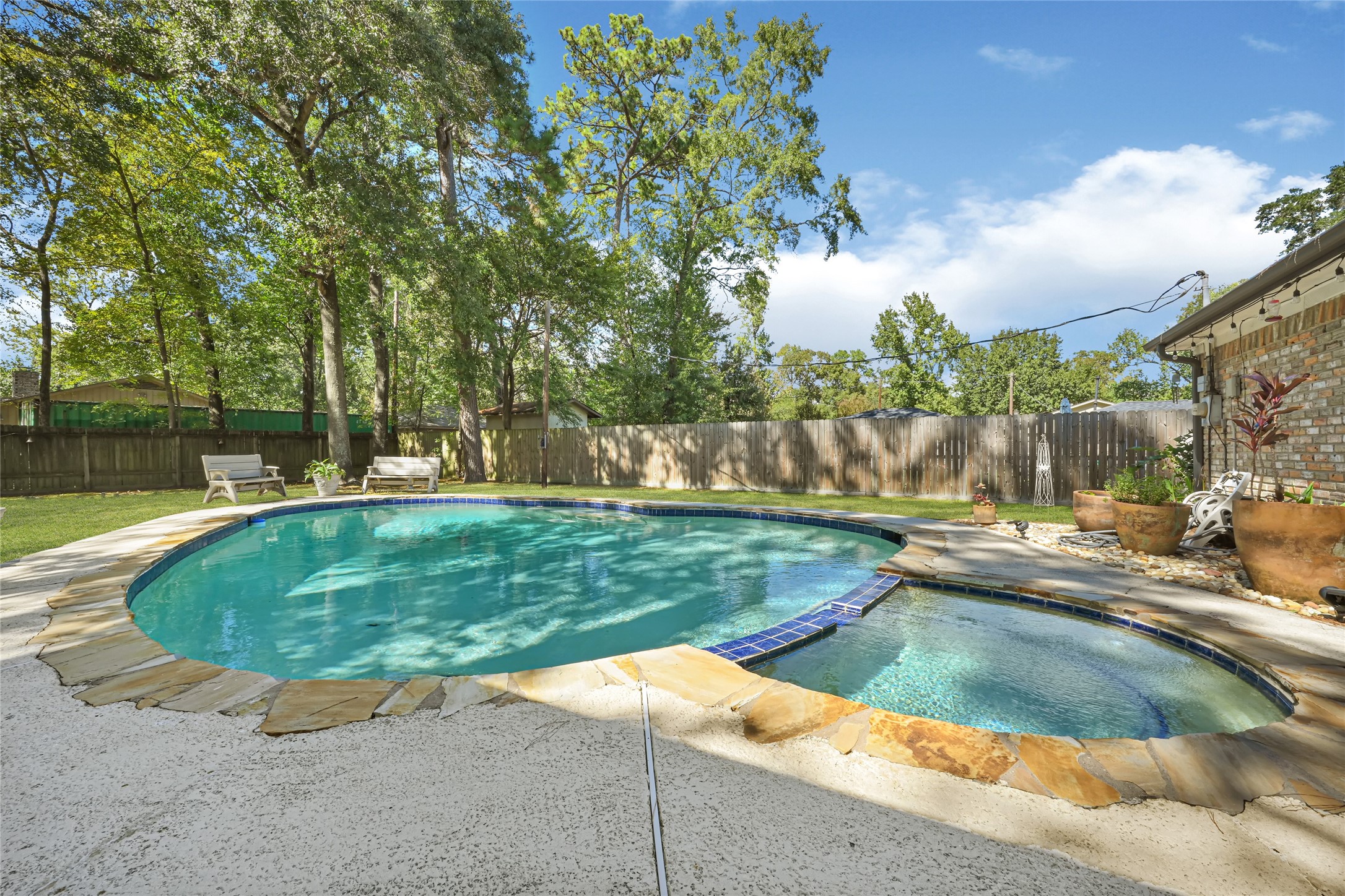Relax in your own private oasis featuring a sparkling pool surrounded by lush trees and a spacious patio, perfect for outdoor entertaining.