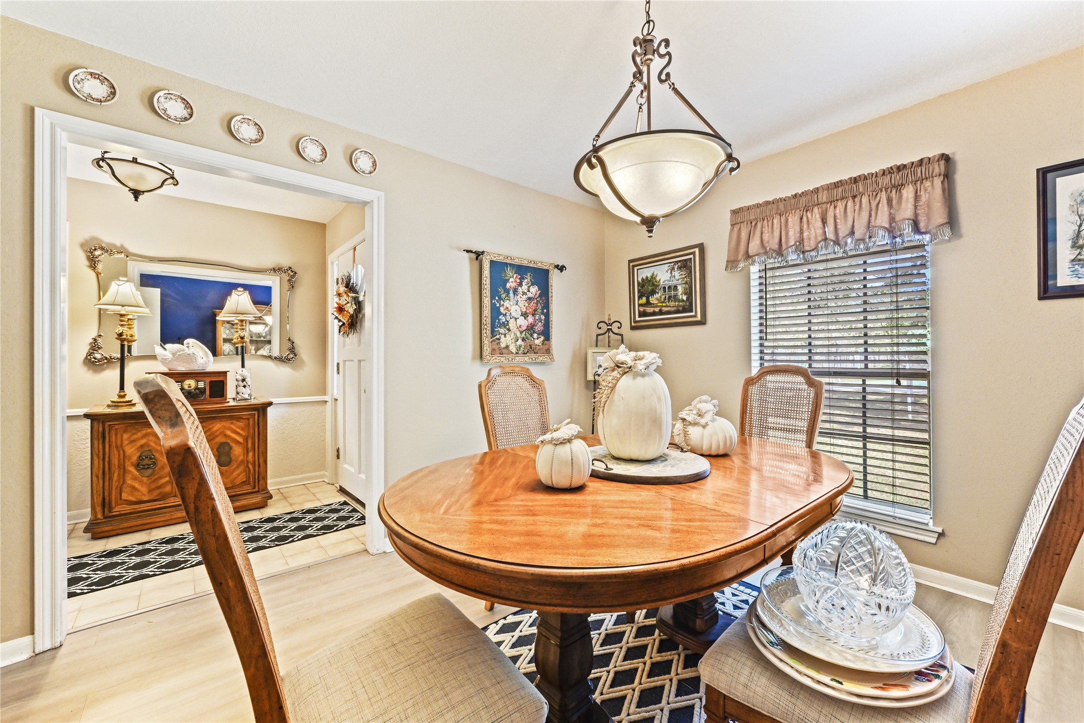 Elegant dining area with abundant natural light, featuring a classic wooden table and tasteful decor, seamlessly connected to a charming hallway with decorative wall plates and sophisticated lighting. Elegant dining area with abundant natural light, featuring a classic wooden table and tasteful decor, seamlessly connected to a charming hallway with decorative wall plates and sophisticated lighting.