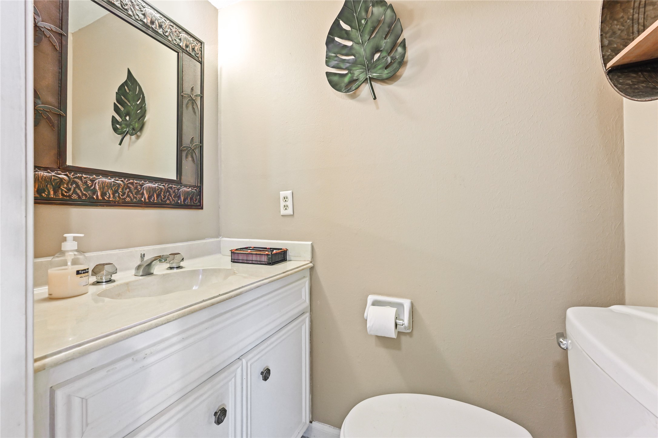 Charming powder room with a sleek vanity, elegant mirror, and tasteful tropical decor accents.