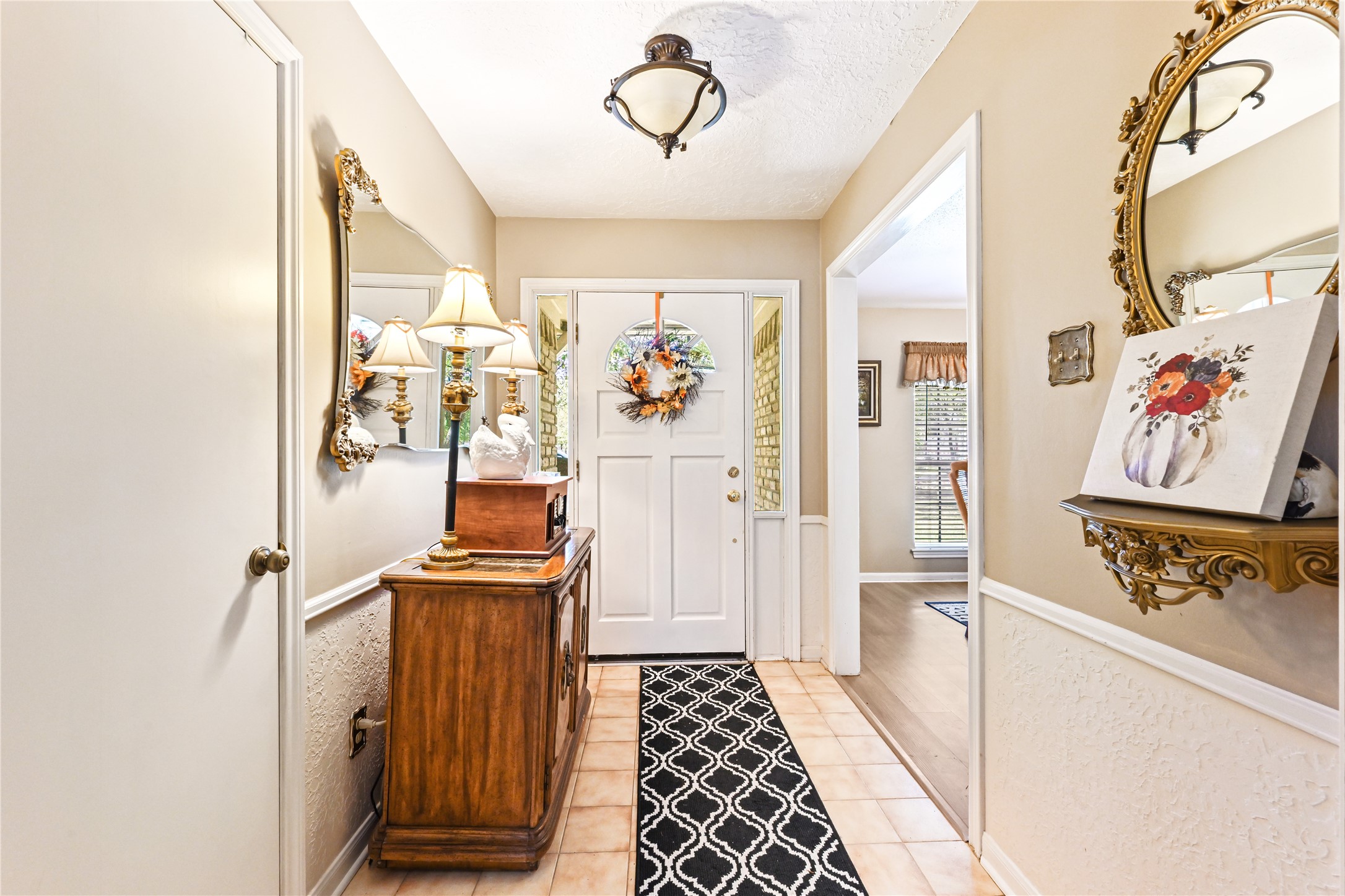 Charming entryway featuring a welcoming front door with a seasonal wreath, elegant wall mirrors, and a classic wooden console table with stylish decor. Charming entryway featuring a welcoming front door with a seasonal wreath, elegant wall mirrors, and a classic wooden console table with stylish decor.