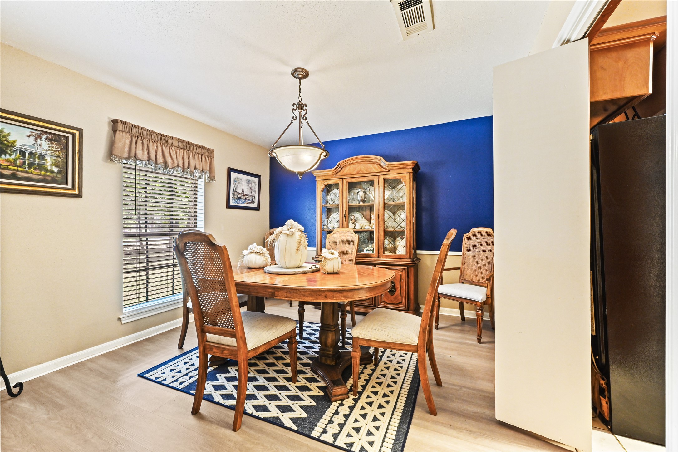 Charming dining room with a bold blue accent wall, elegant chandelier, and wooden furniture, creating a cozy and inviting atmosphere perfect for family gatherings. Charming dining room with a bold blue accent wall, elegant chandelier, and wooden furniture, creating a cozy and inviting atmosphere perfect for family gatherings.