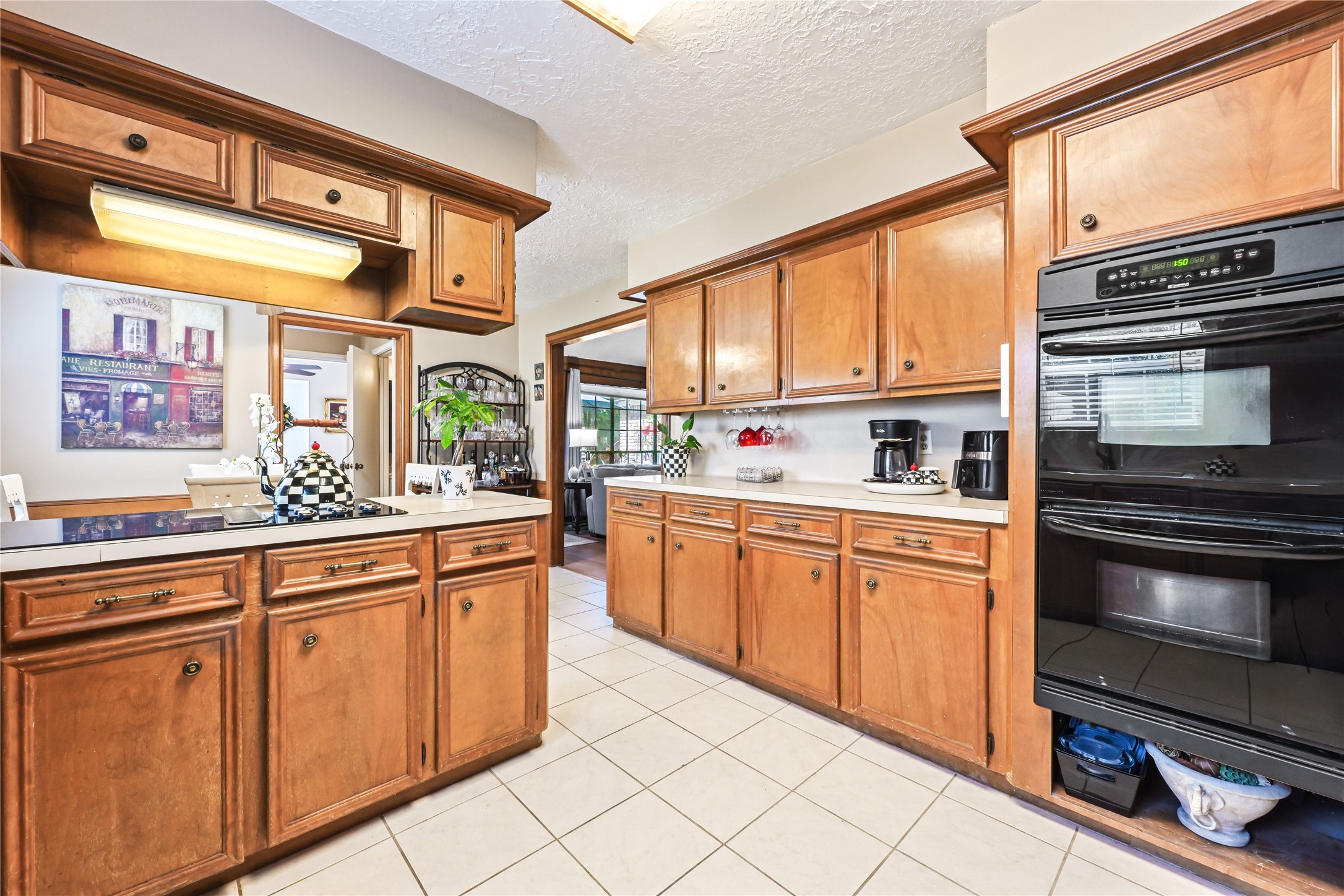Spacious kitchen with warm wood cabinetry, sleek black appliances, and ample counter space, perfect for culinary enthusiasts.