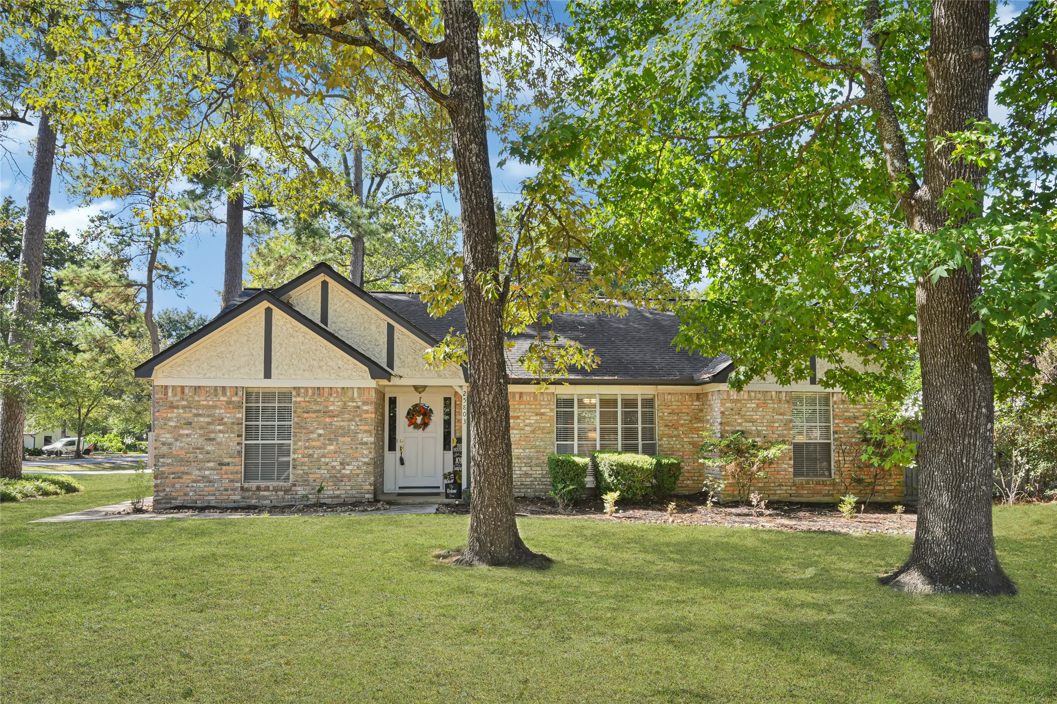Charming brick home nestled among mature trees, offering a spacious lawn and inviting curb appeal.