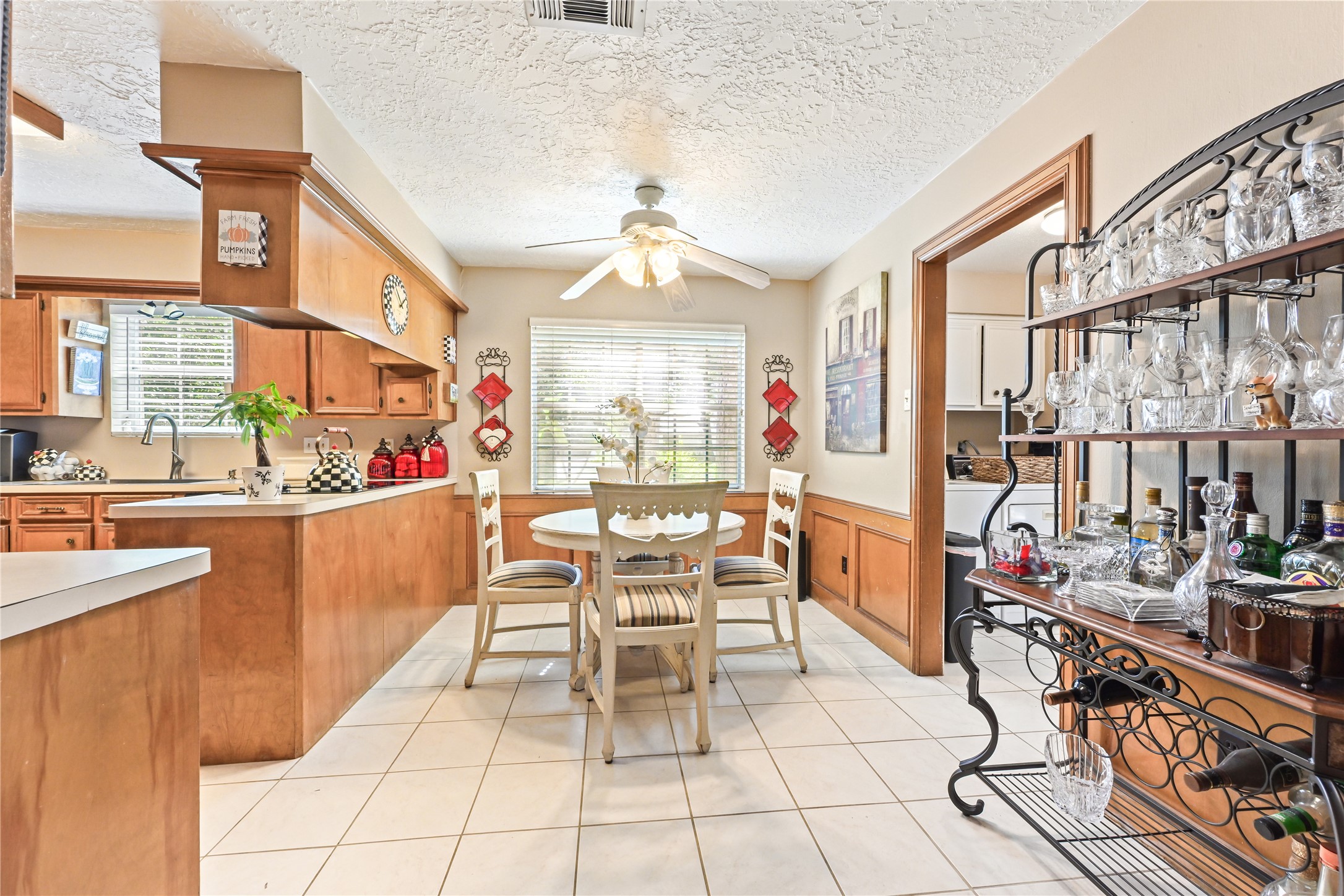 Charming kitchen and dining area featuring warm wood cabinetry, a cozy round table, and ample natural light. A decorative wine rack adds a touch of elegance, perfect for entertaining.