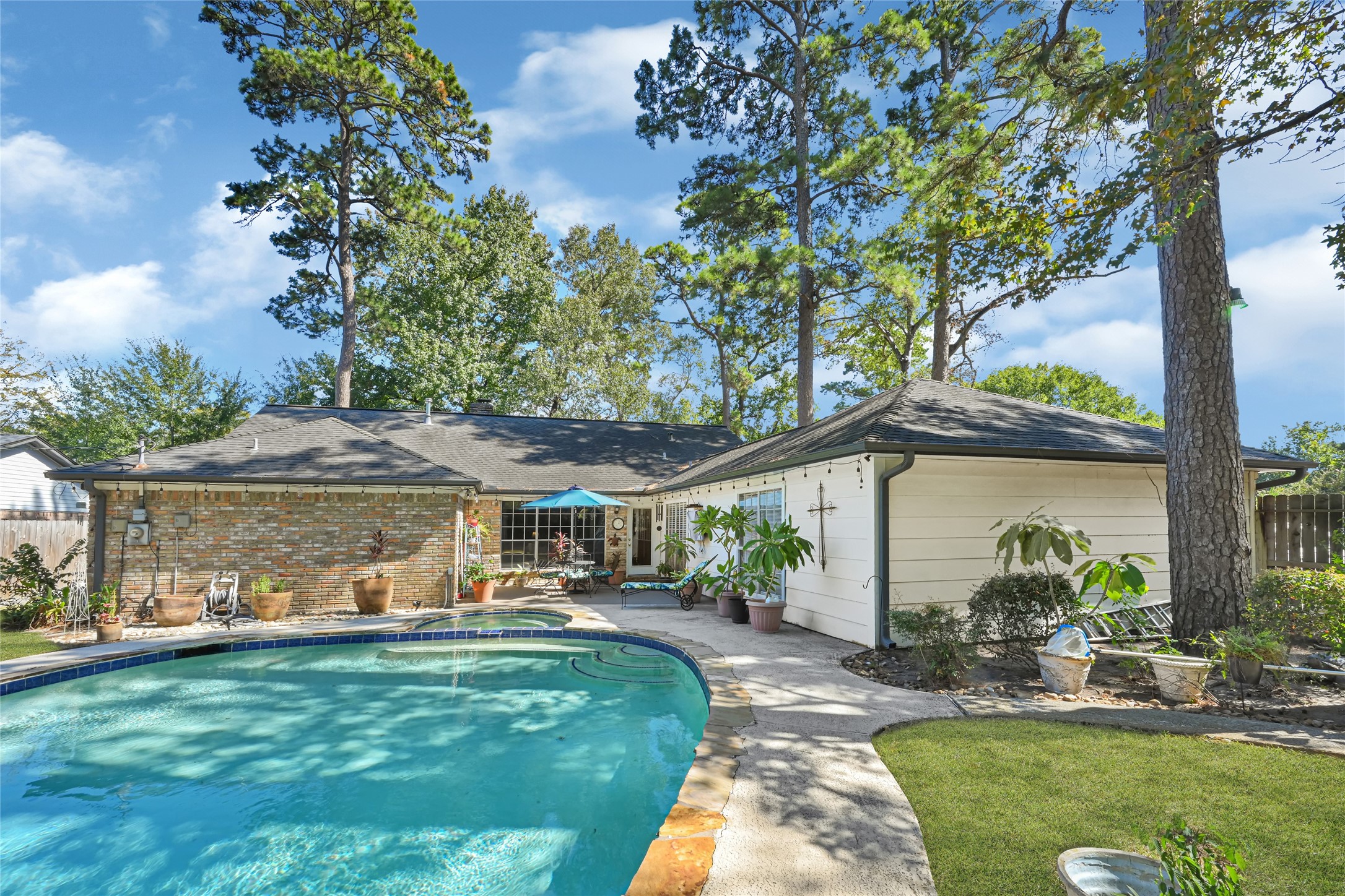 Charming home with a spacious backyard featuring a sparkling pool surrounded by lush greenery and mature trees, perfect for relaxation and entertaining.