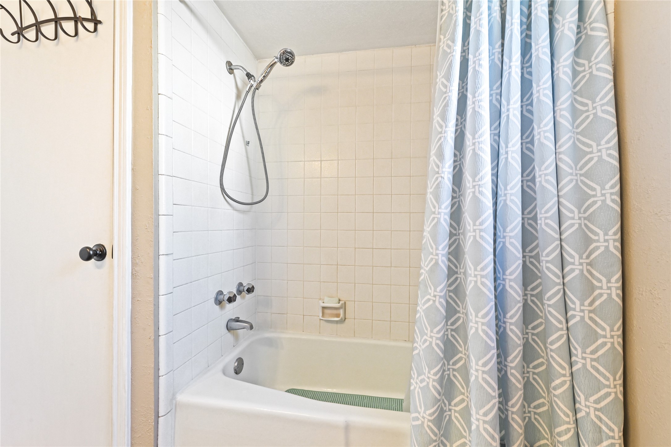 Cozy bathroom features a classic white tiled shower and tub combo, complemented by a stylish patterned shower curtain.