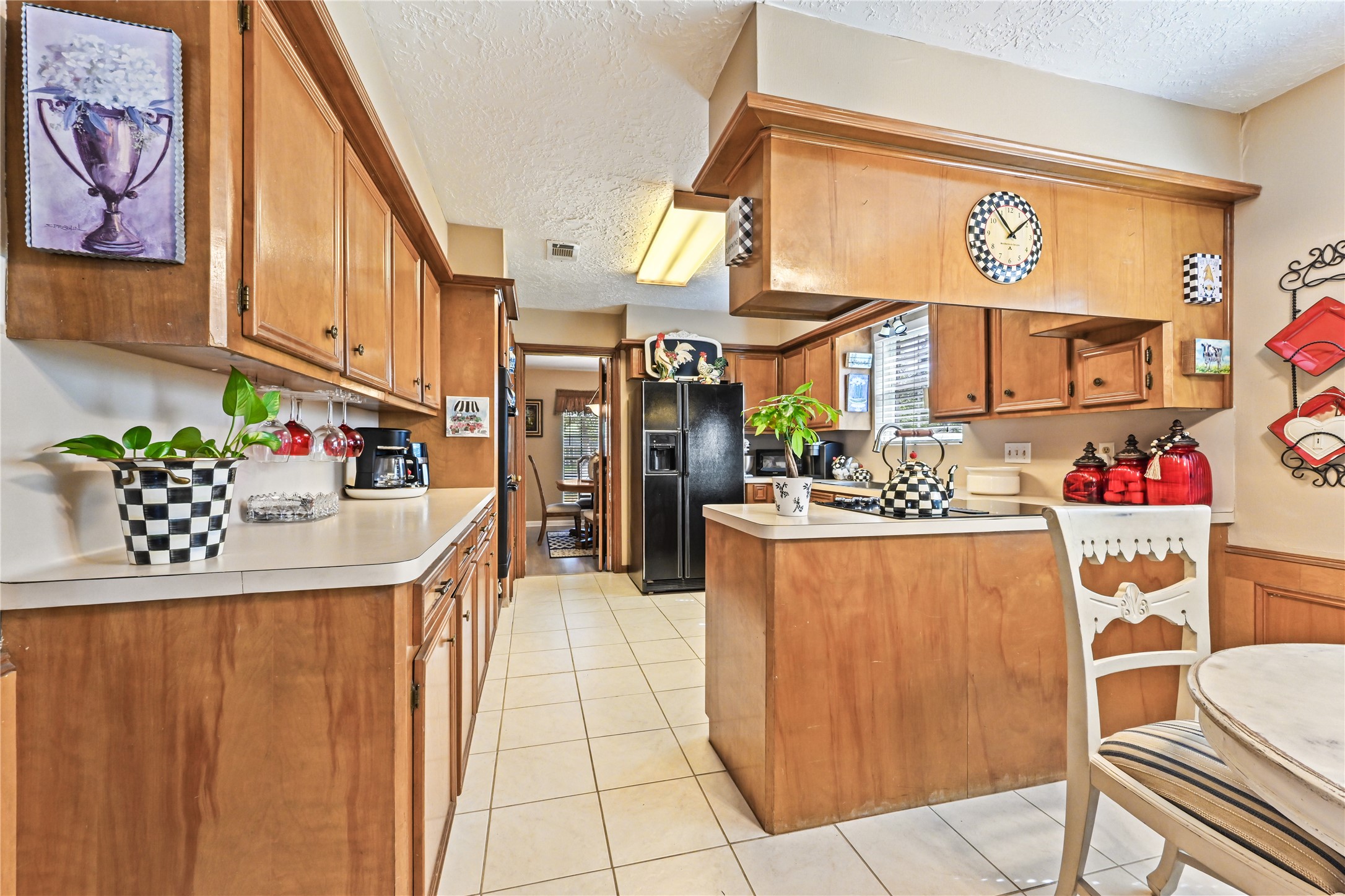 Charming kitchen with warm wood cabinetry, spacious countertops, and stylish checkered accents, featuring modern appliances and a cozy breakfast nook.
