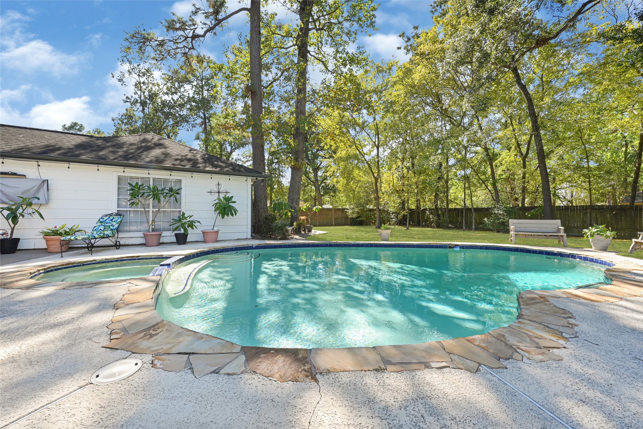 Enjoy a serene backyard oasis featuring a sparkling pool surrounded by lush greenery and ample patio space, perfect for relaxation and entertaining.