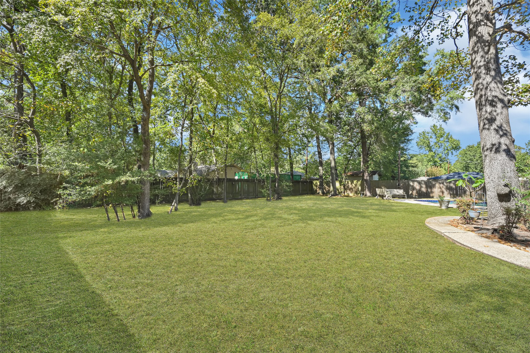 Expansive backyard with lush green lawn and mature trees, offering a serene and private outdoor retreat.