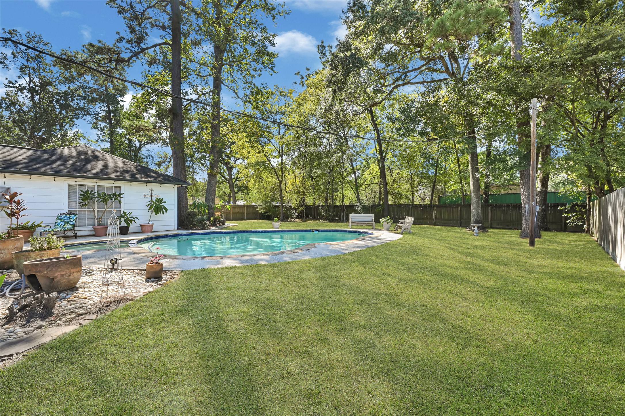 Spacious backyard oasis with a sparkling pool surrounded by lush greenery, perfect for relaxation and outdoor entertaining.