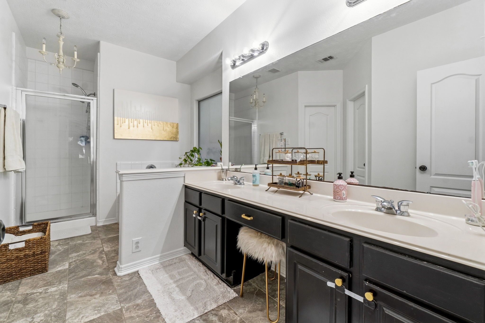 Spacious bathroom featuring a double vanity with elegant black cabinetry, a large mirror, and a walk-in shower.