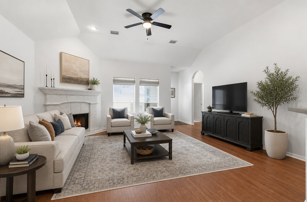 Spacious living room with high ceilings, elegant fireplace, and abundant natural light, featuring cozy seating and modern decor.