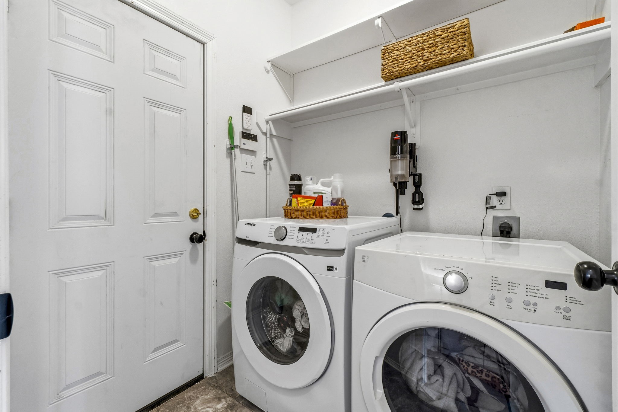 Convenient laundry room equipped with modern washer and dryer, ample shelving for storage, and easy access to the adjacent area.