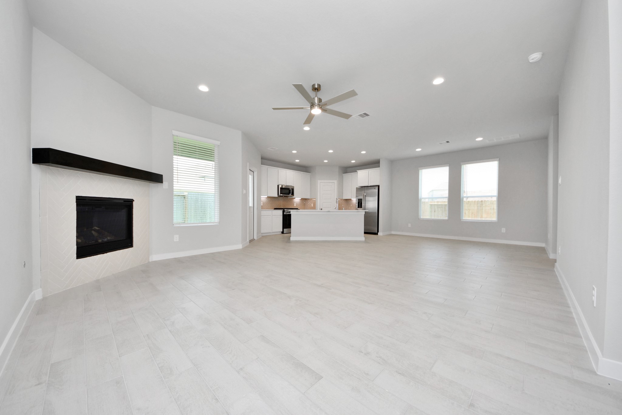 Welcome family and guests to your charming living room! With its high ceilings, recessed lighting, ceiling fan, custom paint, beautiful flooring, and large windows that let in abundant natural light, this room is perfect for gatherings. Sample photo of completed home with similar floor plan. Actual colors and selections may vary.