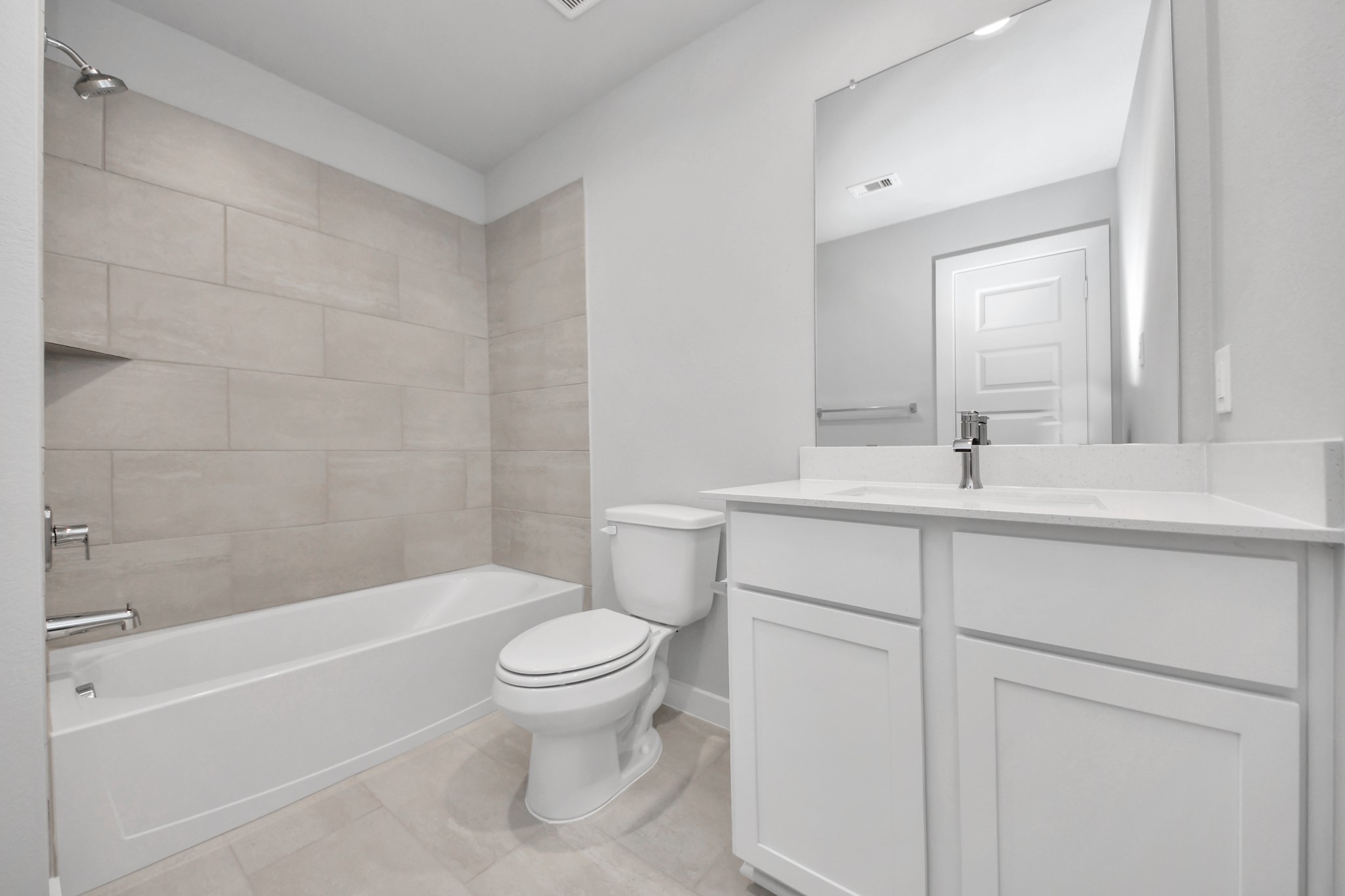 Secondary bath features tile flooring, bath/shower combo with tile surround, light stained wood cabinets, beautiful light countertop. Sample photo of completed home with similar floor plan. Actual colors and selections may vary.