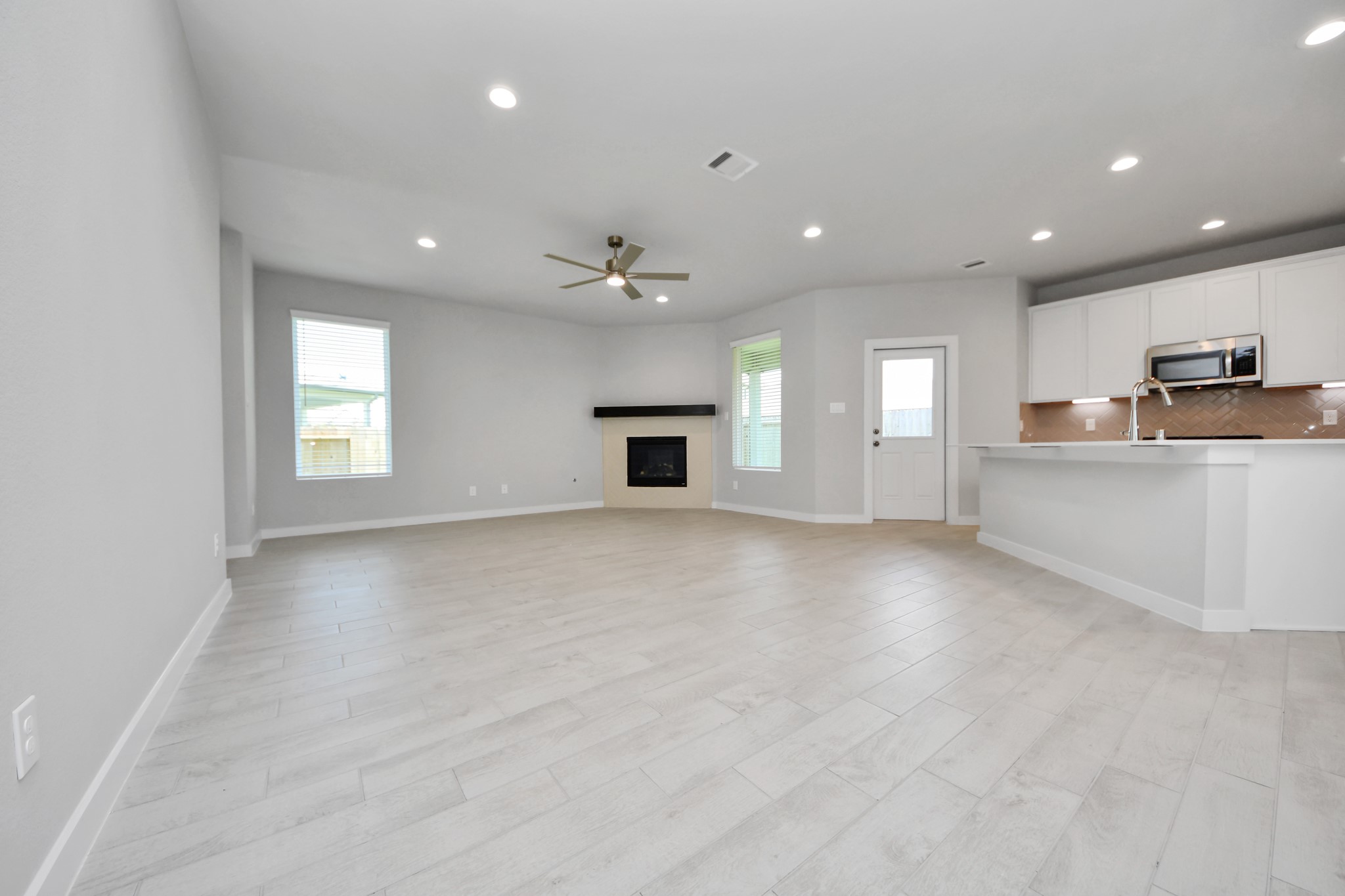 Relax and unwind in this inviting family room, illuminated by abundant natural light streaming in through tall windows, complemented by high ceilings and stunning flooring. Stay comfortable year-round with the gentle breeze from the ceiling fan, creating the perfect atmosphere for family gatherings. Sample photo of completed home with similar floor plan. Actual colors and selections may vary.