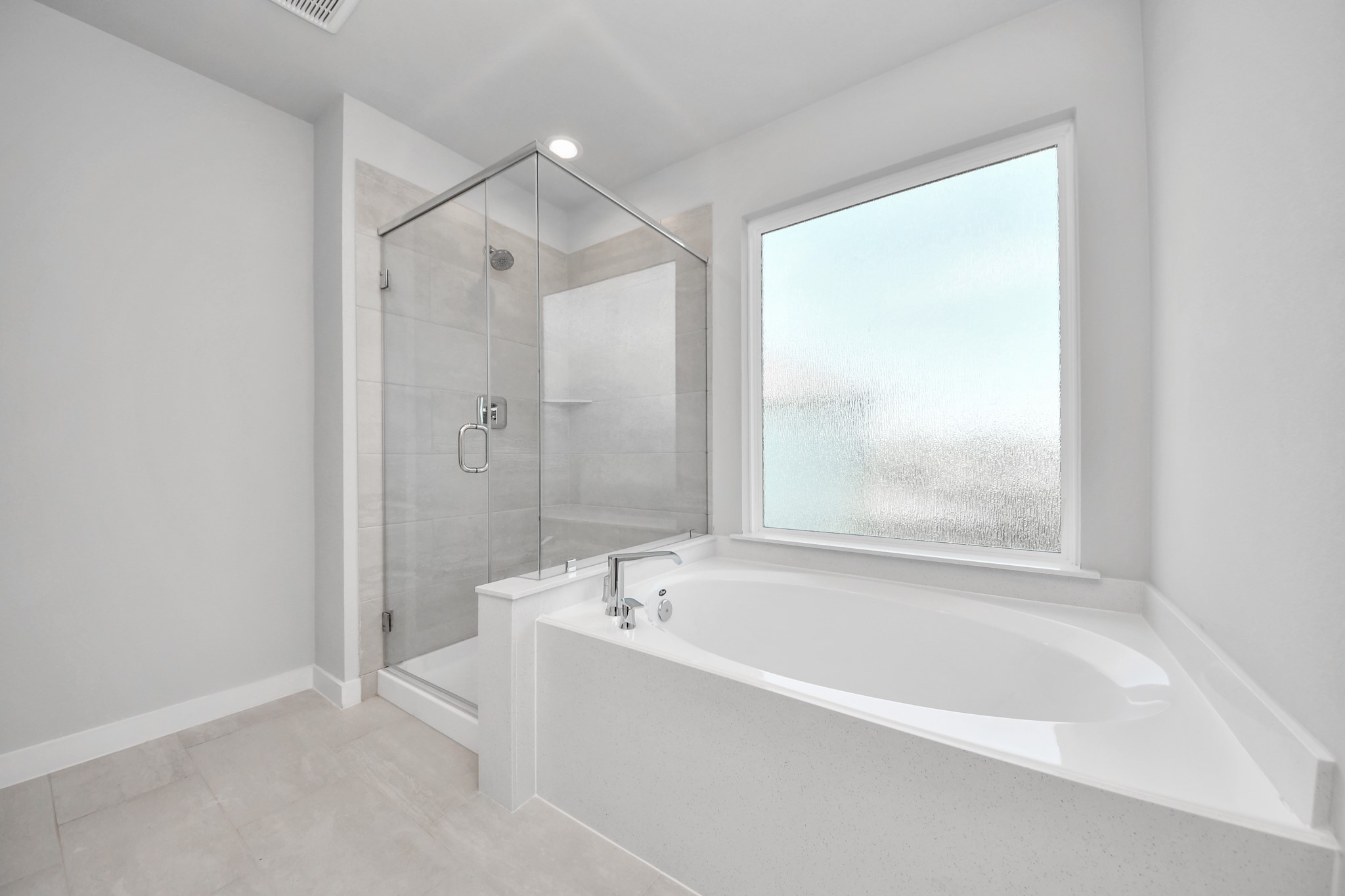 Escape to a spa-like oasis in this primary bathroom. Enjoy a walk-in shower with tile surround, a separate garden tub with custom detailing, and an elegant vanity featuring light countertops, modern hardware, and beautiful recessed lights. Experience luxury and relaxation in every detail. Sample photo of completed home with similar floor plan. Actual colors and selections may vary.