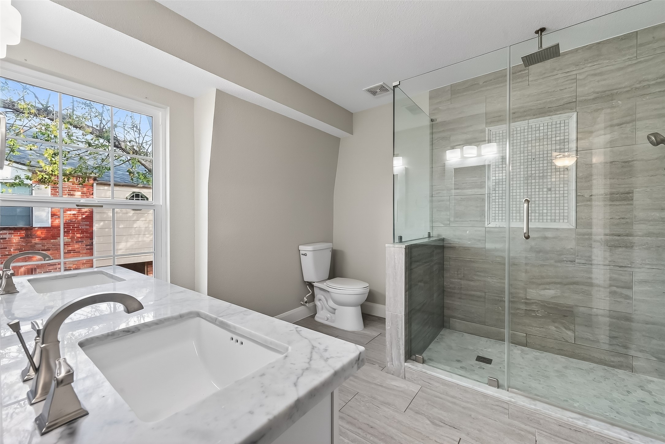 Spa-like primary bath featuring custom shower, upgraded fixtures, and elegant marble countertops.