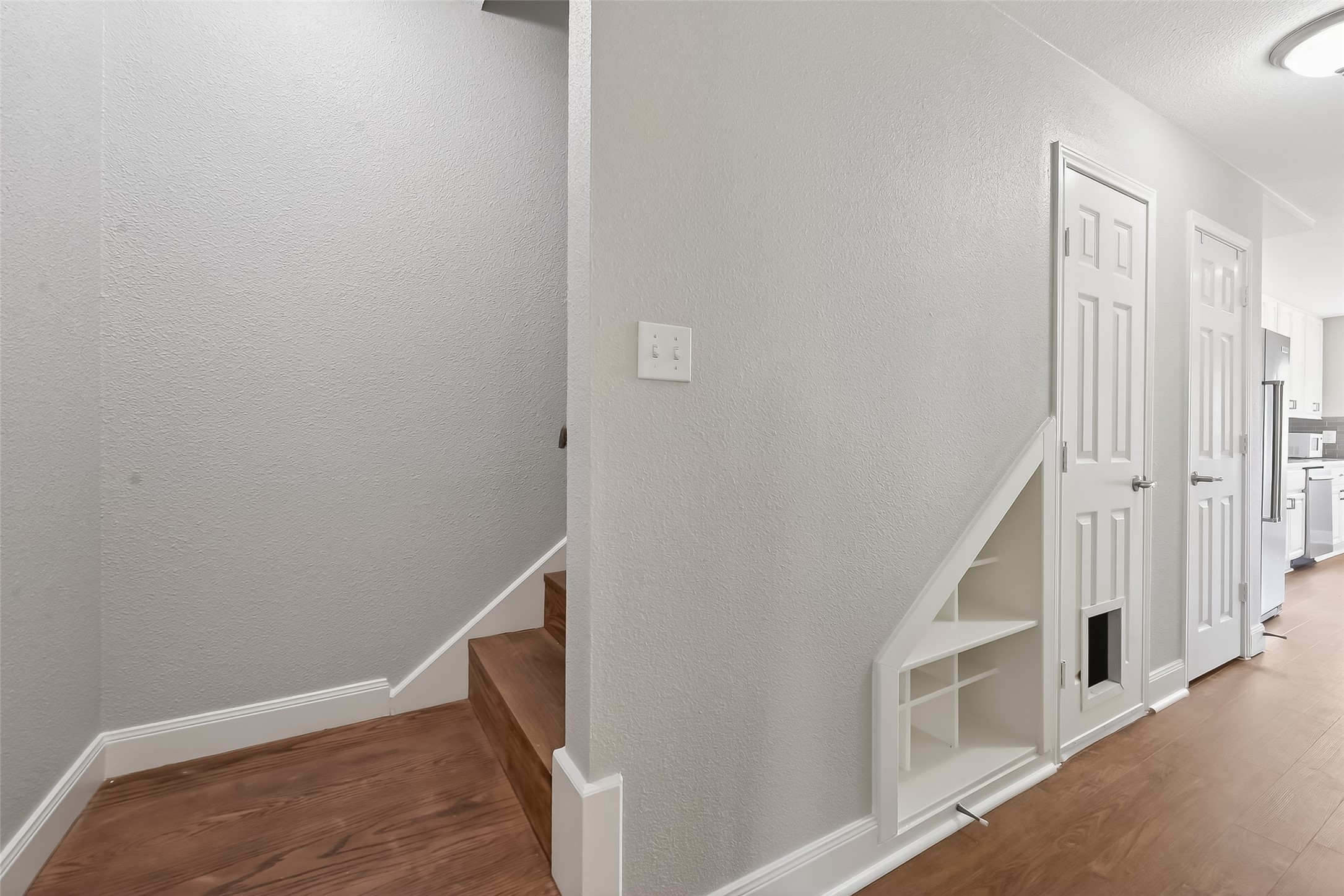 Updated stairwell with wood tread stairs, built-in shelving, and additional storage closet offering functional organization and smart use of space in this Houston townhom