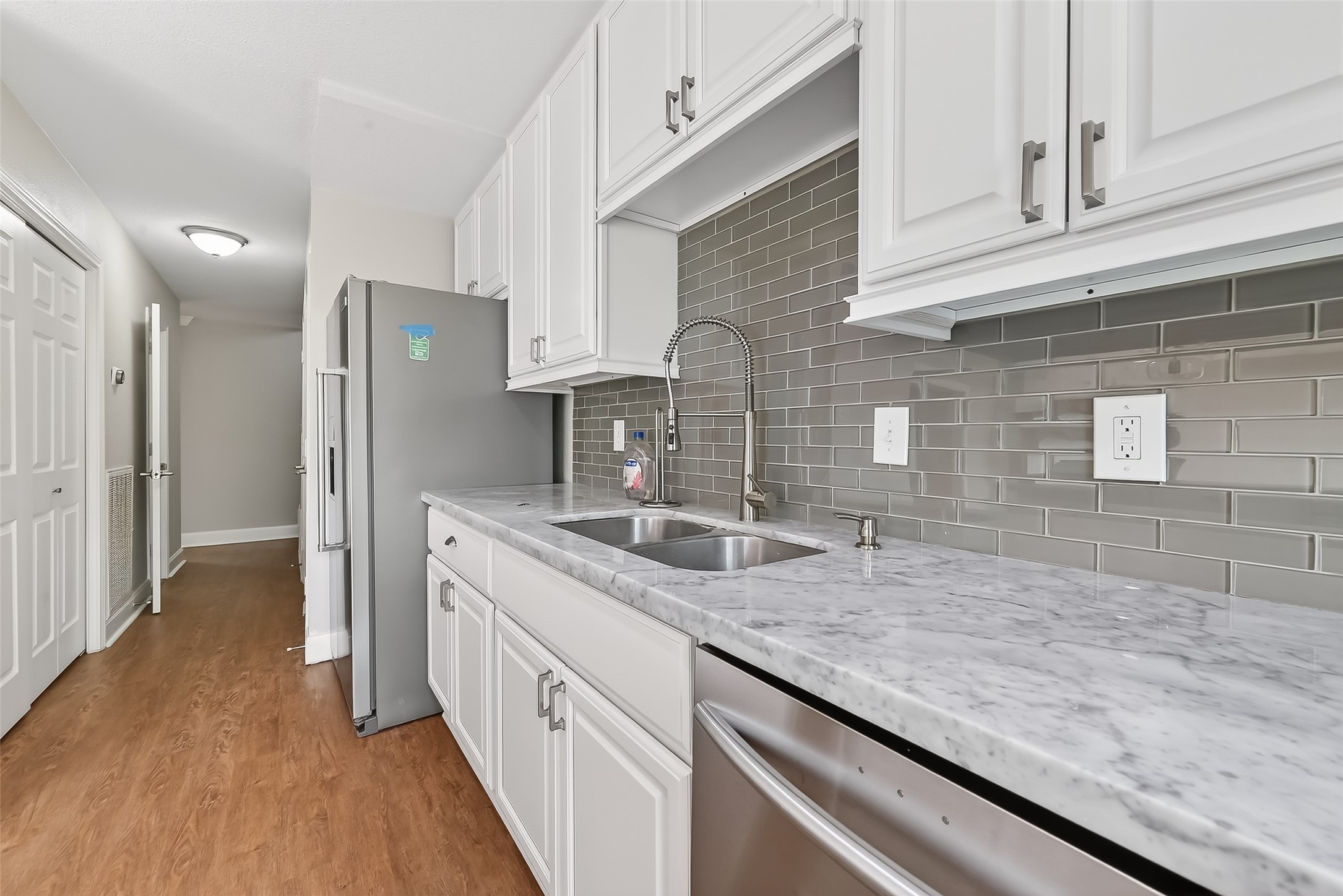 Beautifully renovated kitchen featuring KitchenAid refrigerator, marble countertops, and abundant cabinet storage.